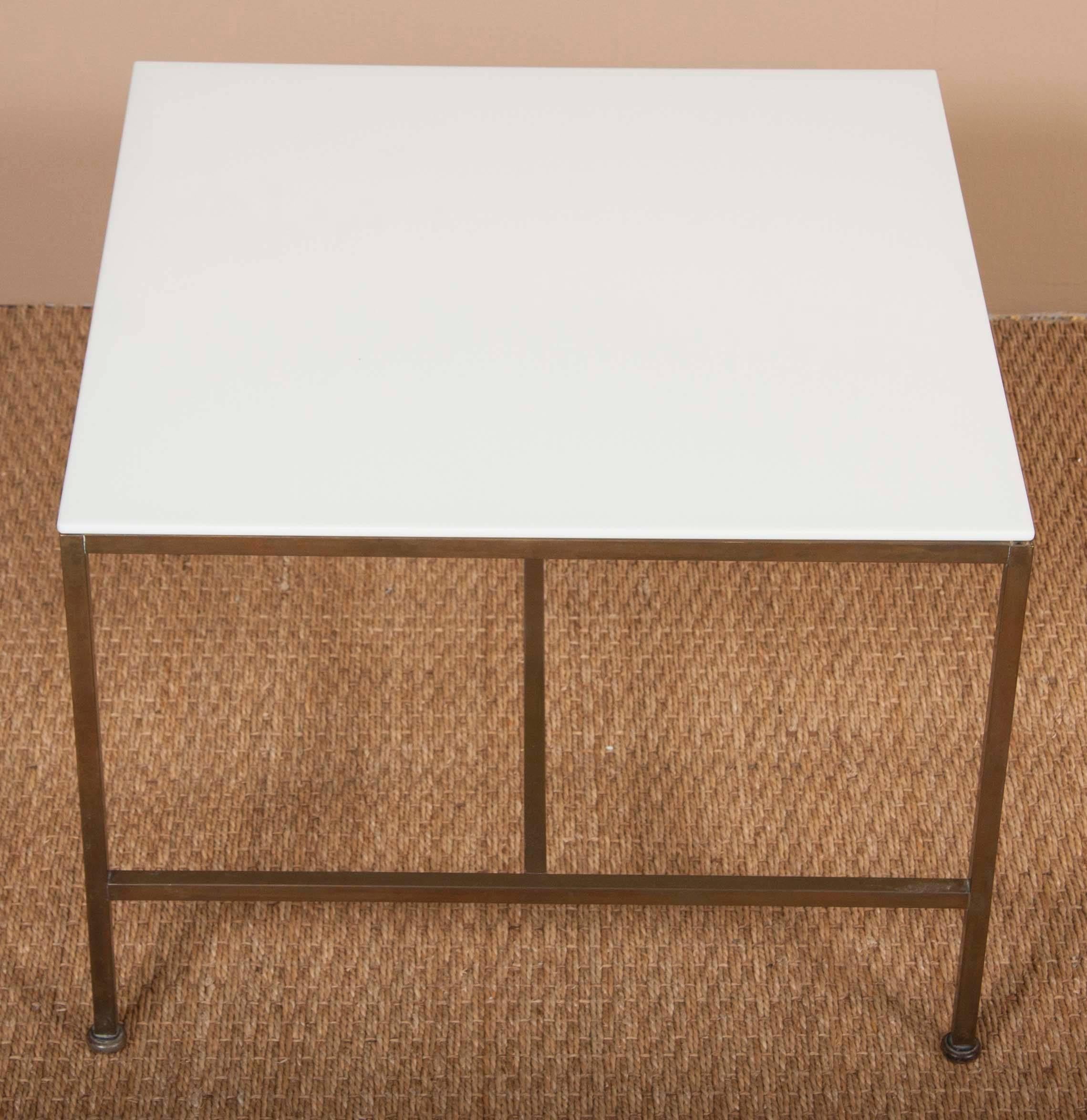 A matched pair of Paul McCobb side tables with Vitrolite glass tops over square brass supports.   Dimensions are exactly the same however one has hollow square tubing and the other uses solid square tubes. 