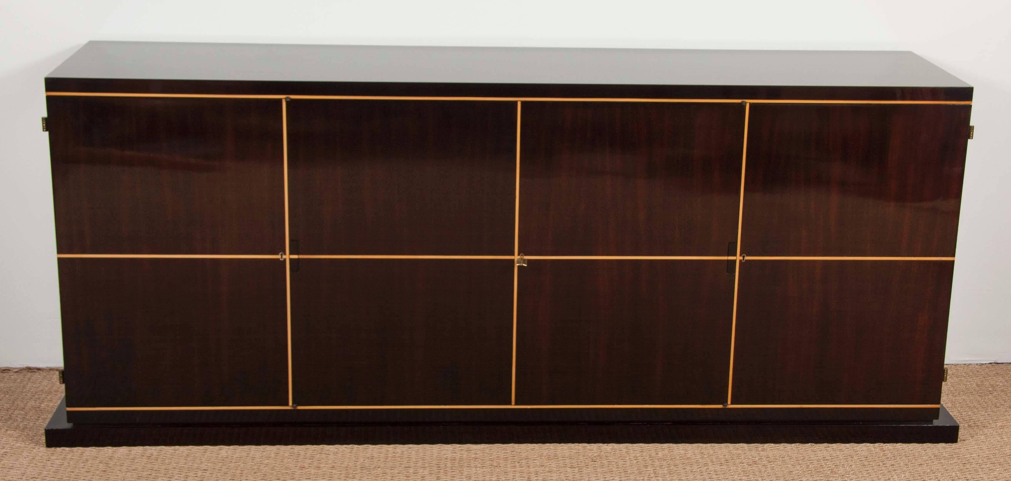 A lacquered mahogany brass banded sideboard with maple inlay by Tommi Parzinger. 

Branded: 