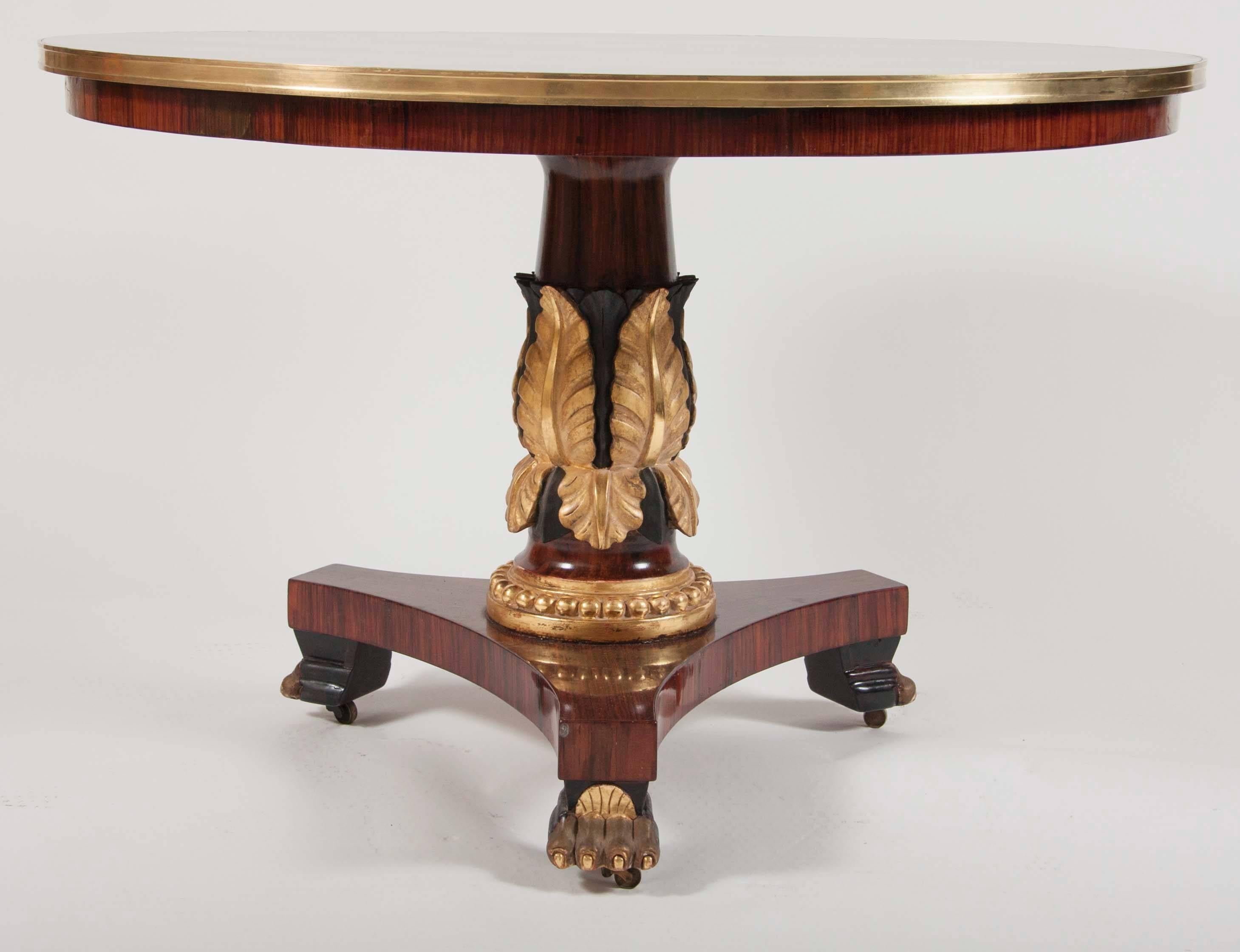An English Regency mahogany center table with a gilded leaf-carved, pedestal and segmented inlaid top.
