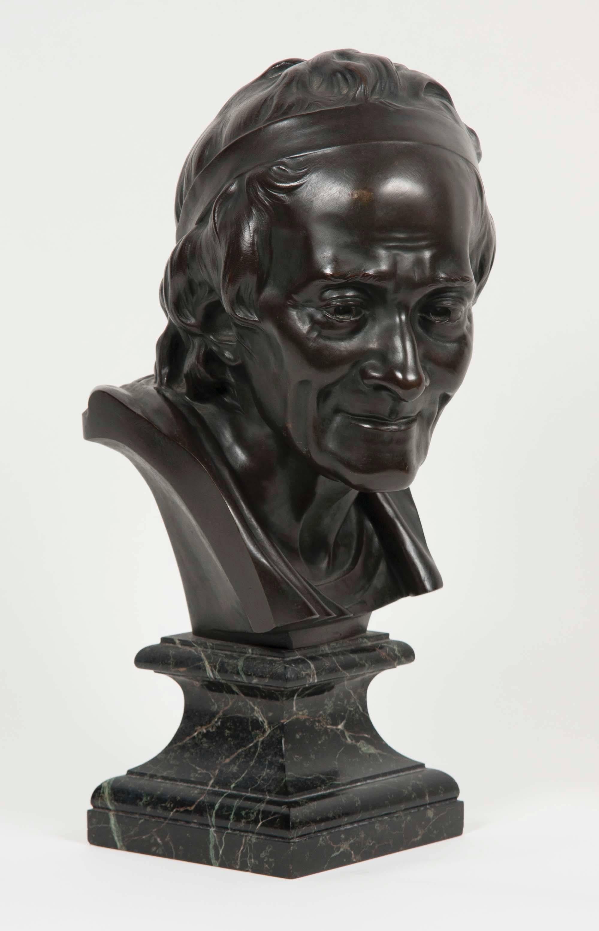 An early 20th century bronze bust of Voltaire after Jean Antoine Houdon, on black and white square marble base.