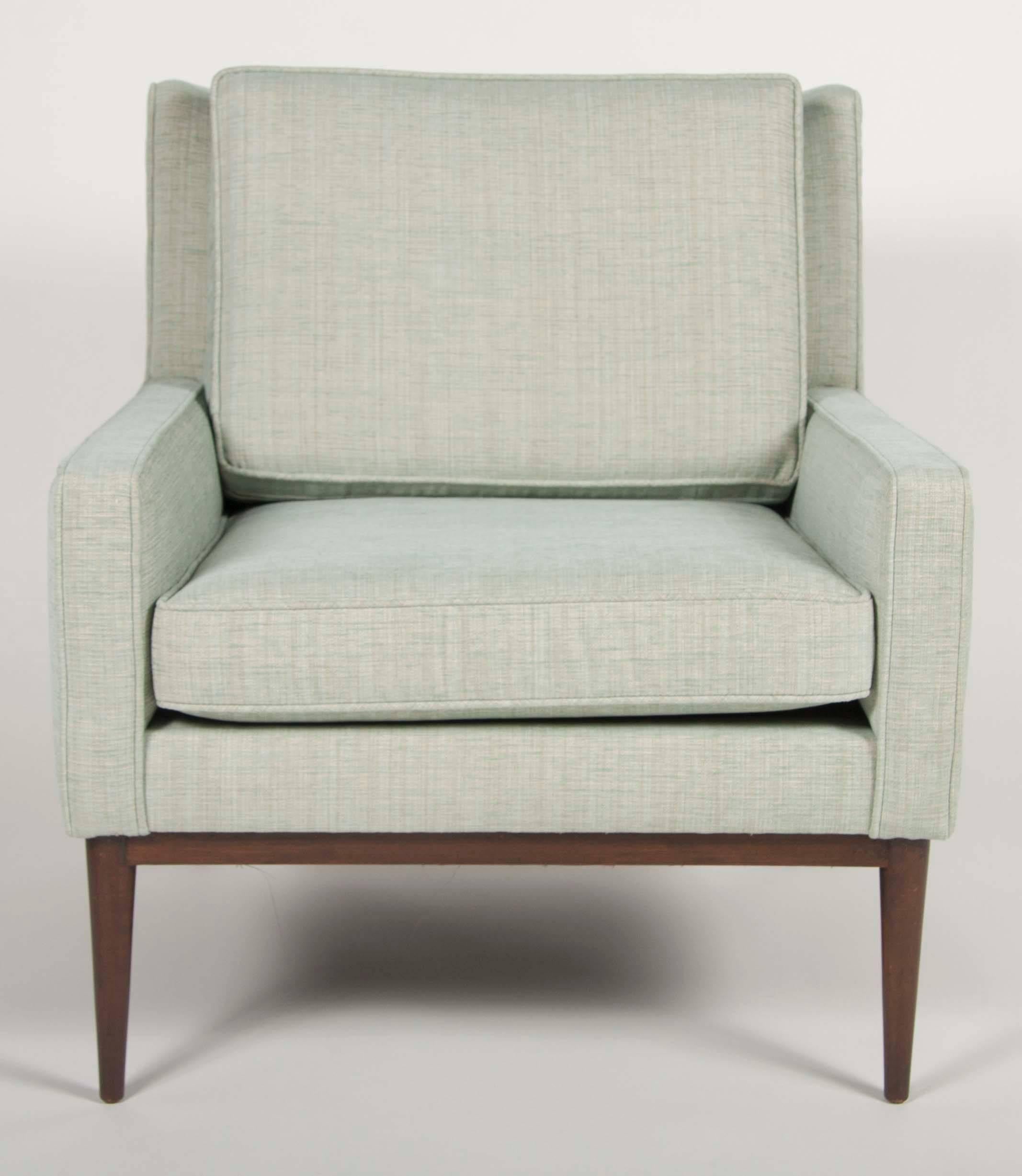 A newly upholstered armchair designed by Paul McCobb having walnut legs and apron.