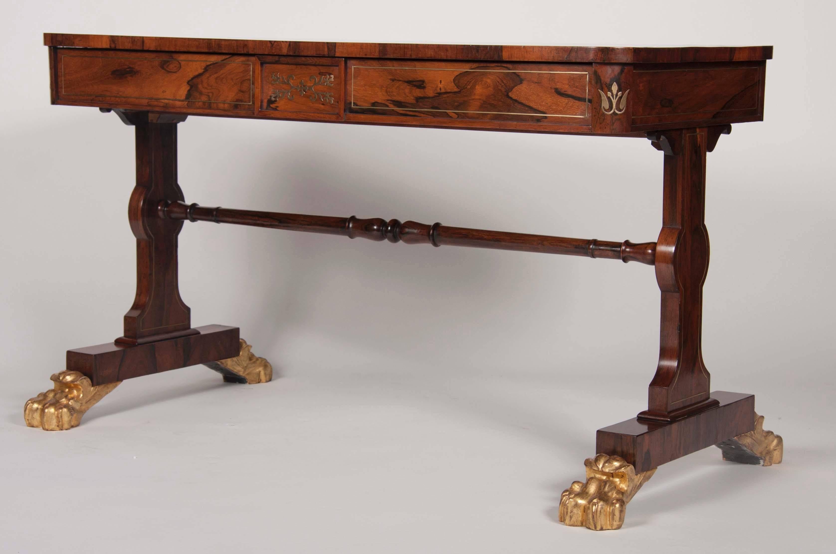 An English Regency, brass inlaid, rosewood library table with gilt paw feet.
  