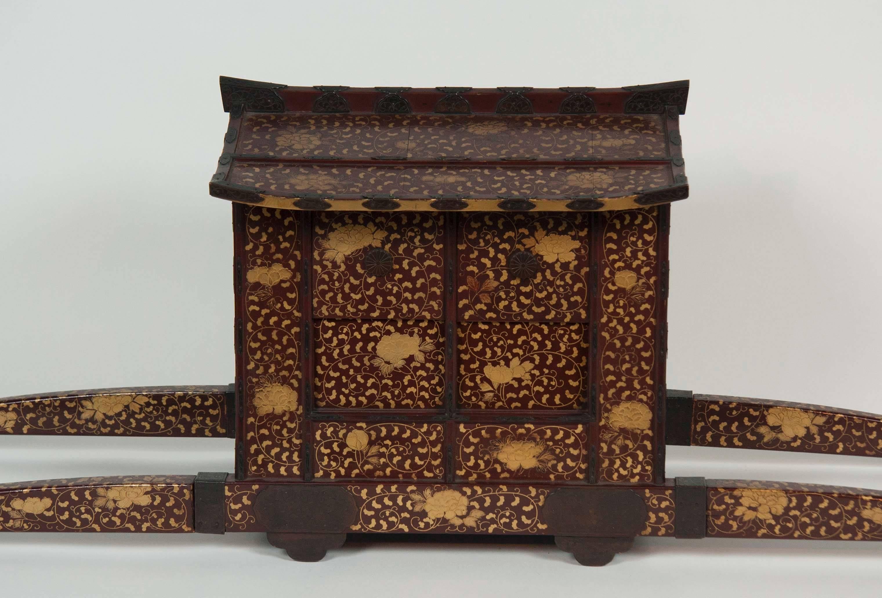 A Japanese Edo-Meiji period Palanquin chair for the childrens festival. The form with sliding and hinged doors, decorated in gold hiramaki-e with peonies and scrolling foliage on a dark reddish-brown.
