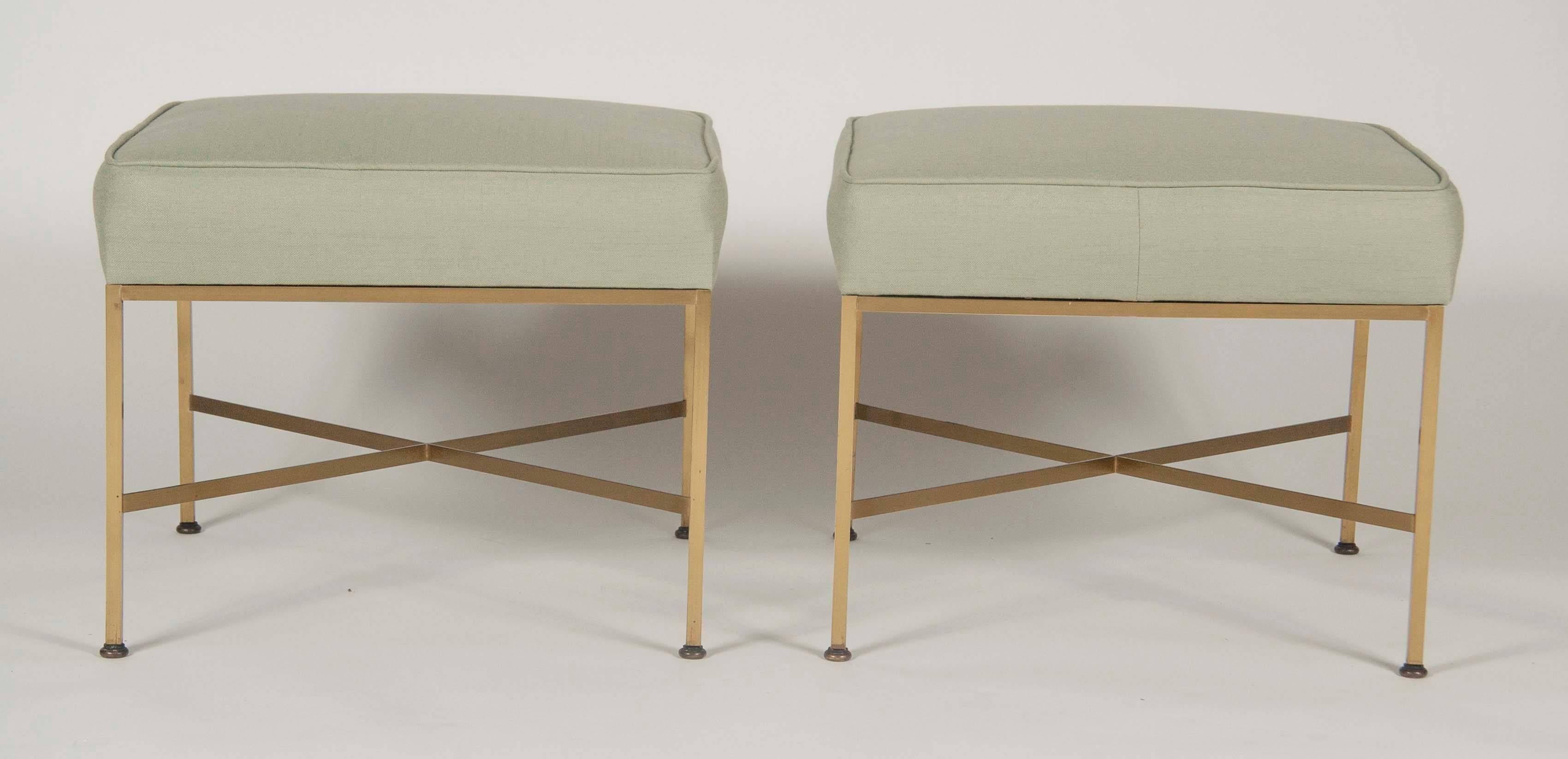 A pair of X-base, brass stools designed by Paul McCobb. Produced by Calvin. This pair has been newly reupholstered.