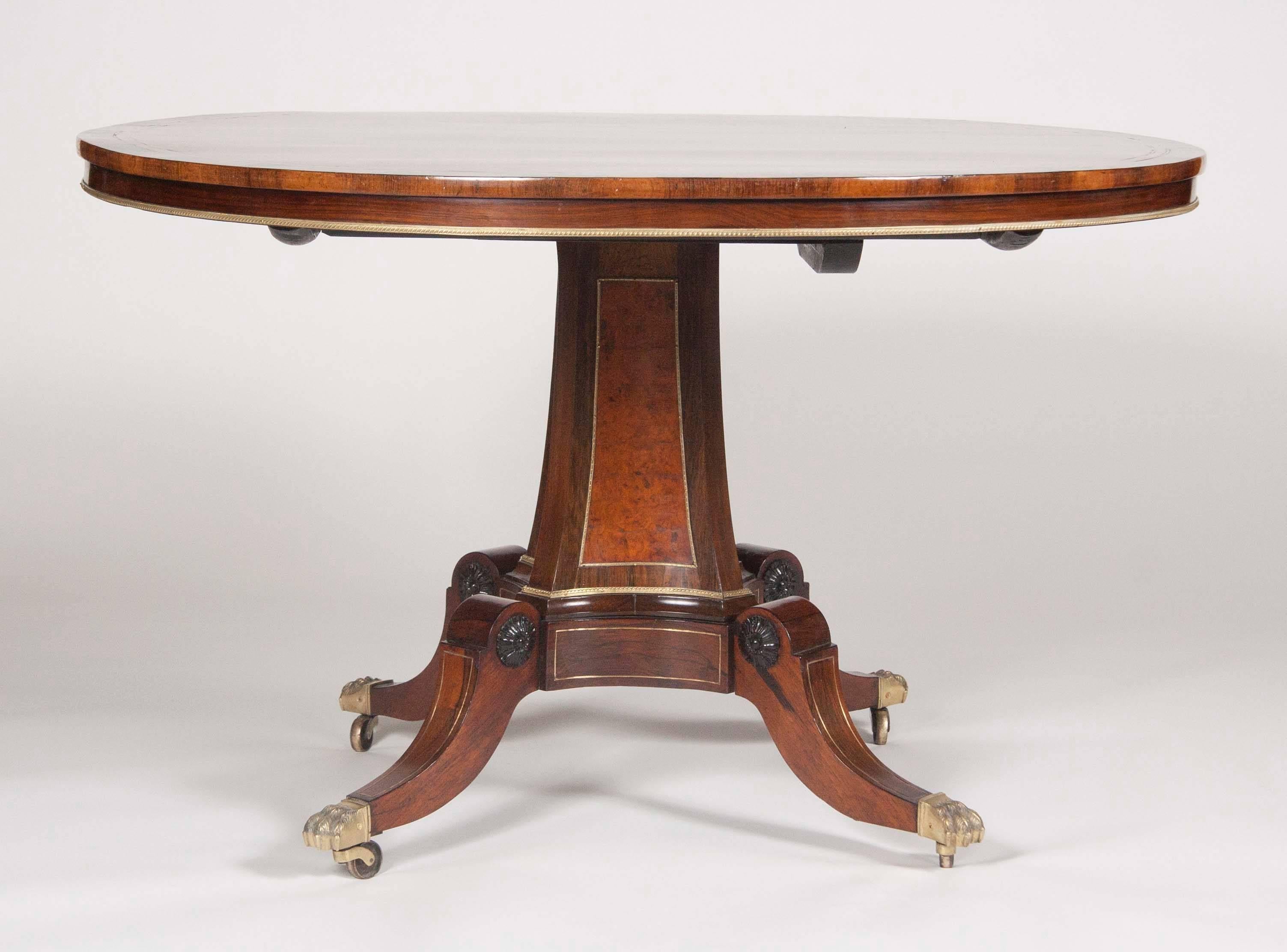 A calamander banded rosewood centre table with gilt bronze mounts and specimen wood elements. The central panel of the concave pillar is burl wood. The swept legs terminate at ebony florets. George Oakley was one of the foremost Regency furniture