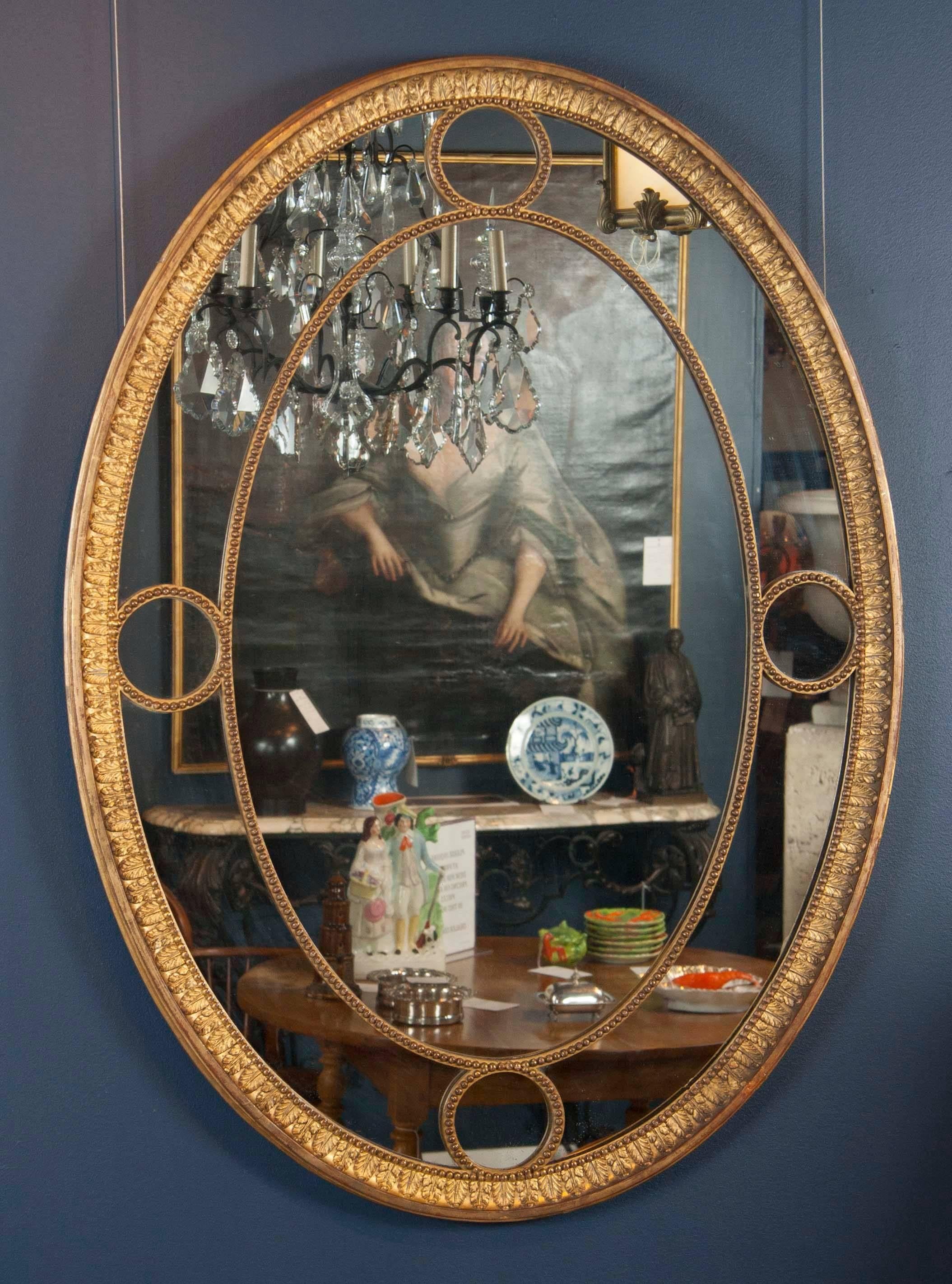 A pair of English giltwood George III period oval mirrors with original glass and gilding.
