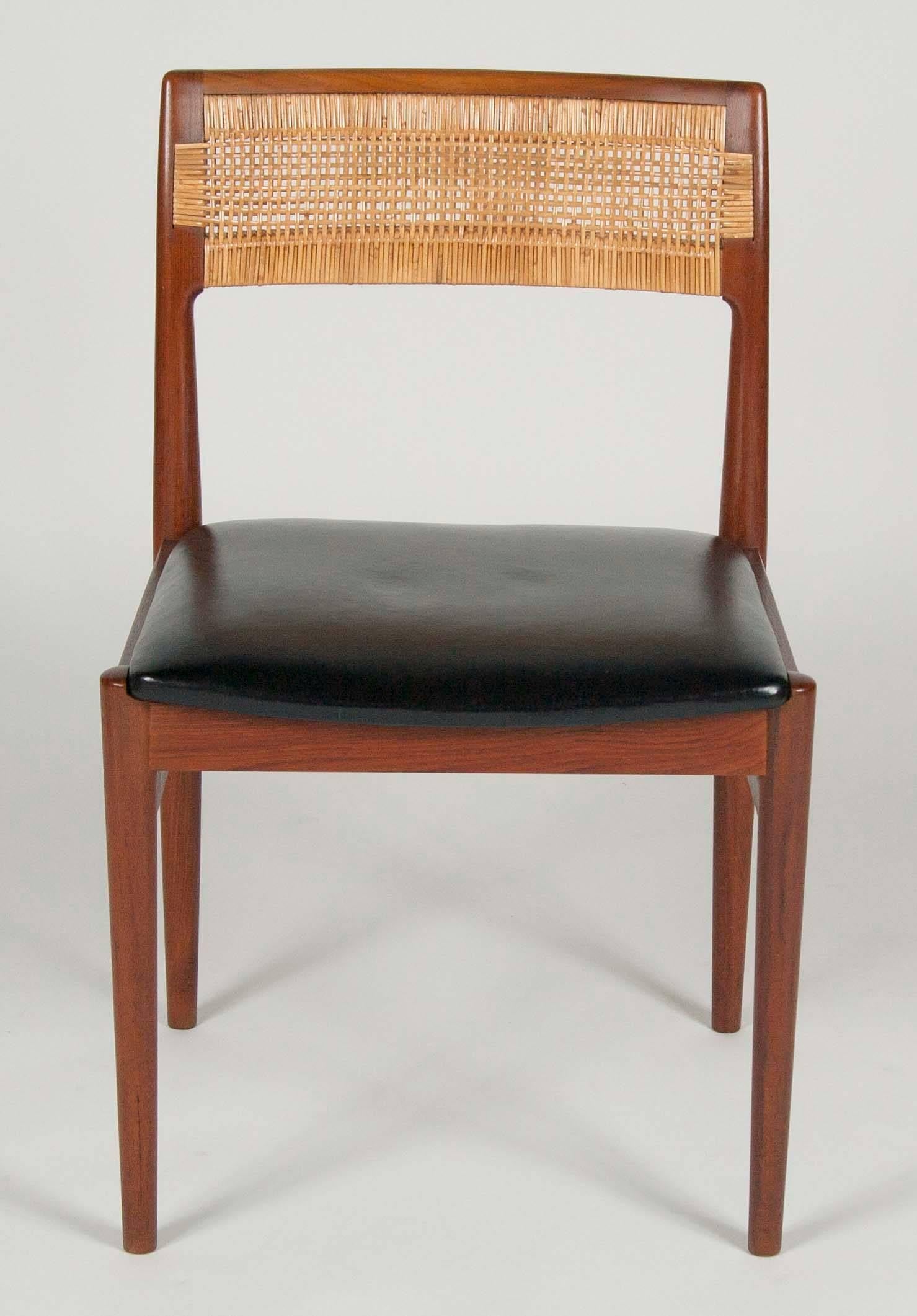 A set of four teak side chairs by Erik Worts with leather seats and caned back rests. Design W26. Newly re-caned.