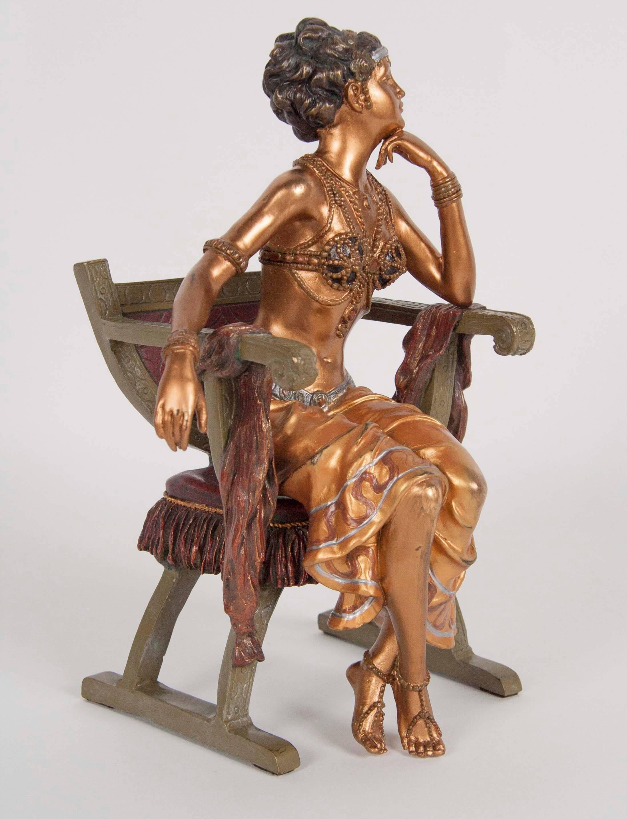A two-piece bronze of an Orientalist woman in a chair signed Bergman, cold painted and gilded.