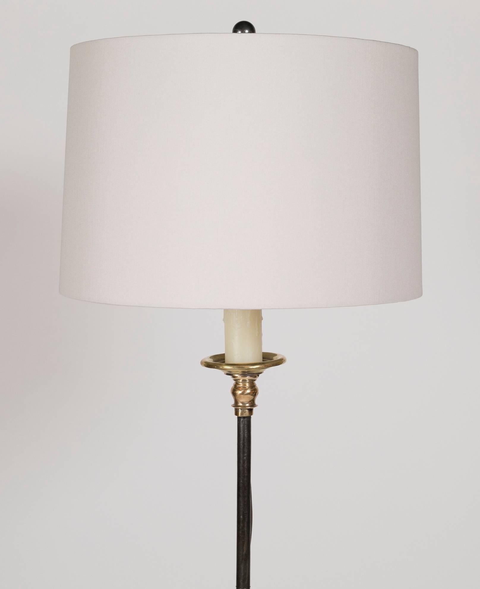 A wrought iron floor lamp with turned brass accents.