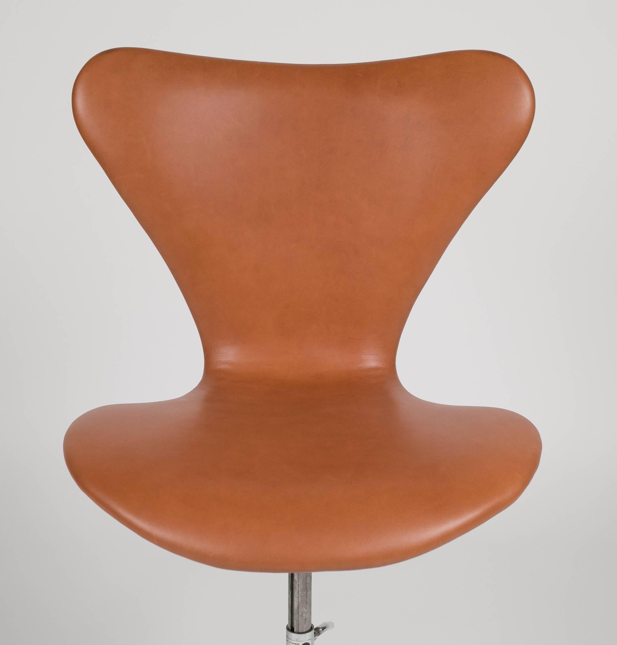 A swivel desk chair by Arne Jacobsen upholstered in natural Sorensen leather. This chair is model 3117, designed by Arne Jacobsen for Fritz Hansen. Marked on metal base and under seat.