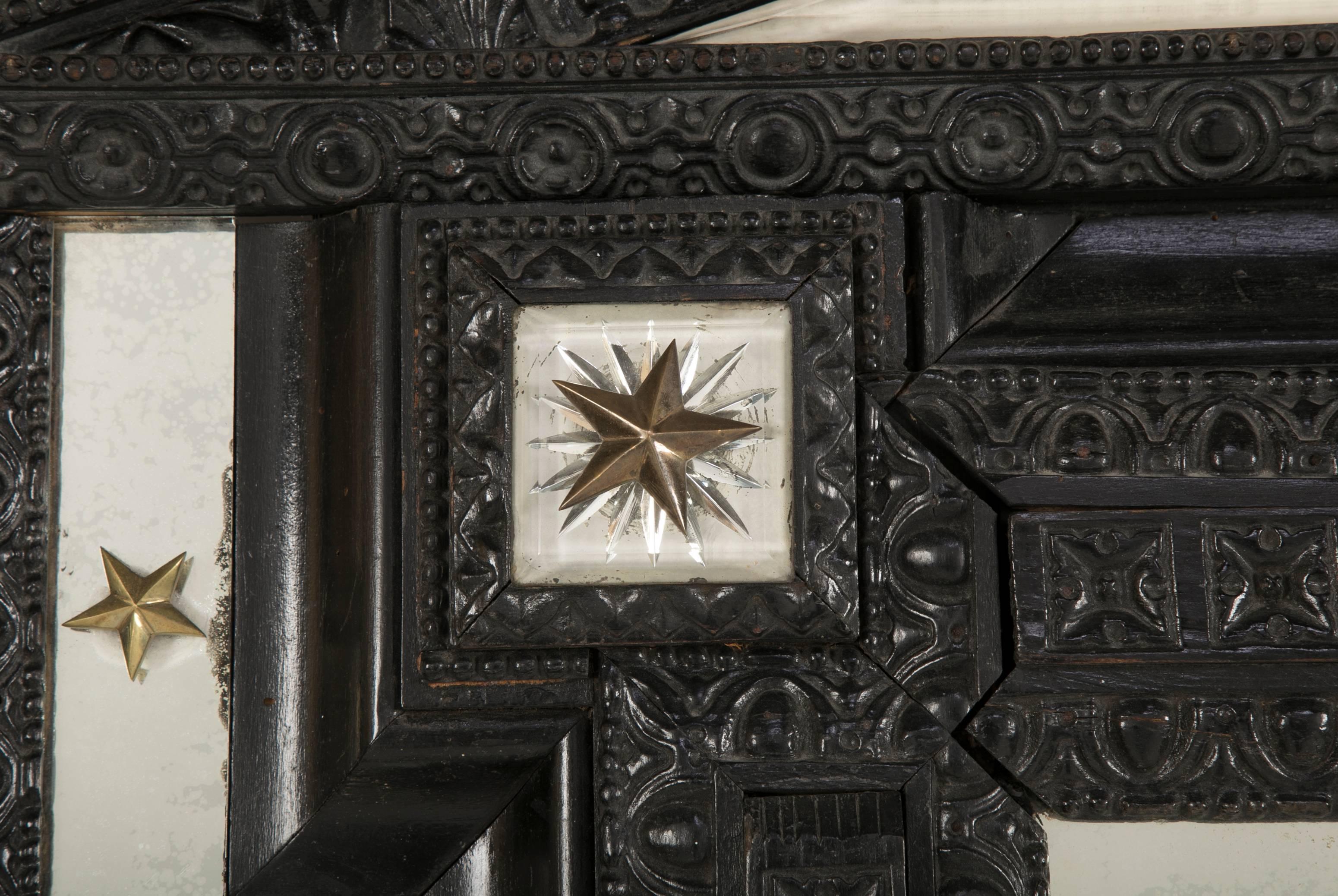 A Flemish ebonized and carved Baroque style mirror. Mirror having cut-glass and gilt star mounts.