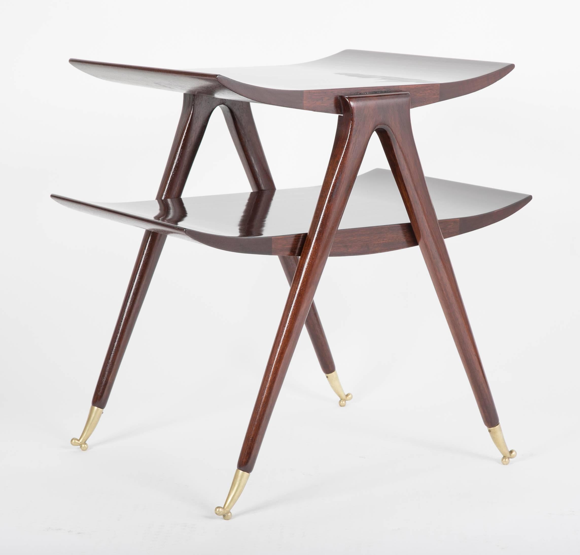Mid-20th century Italian side table attributed to Ico and Luisa Parisi. A two-tiered walnut table with curved ends, brass tapered sabots with ball feet. This slick designed high quality table also presents similarities with smaller designs