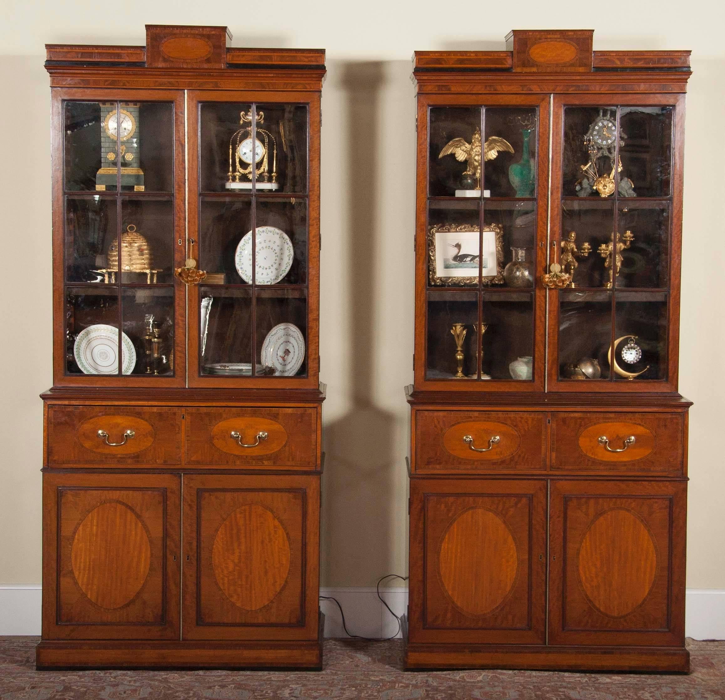 Una rara quasi coppia di segretarie o librerie del periodo Regency inglese con intarsi in palissandro, ebano, mogano e legno di raso. I cassetti della parte anteriore sono di colore leggermente diverso, così come la pelle interna. Anche il numero di
