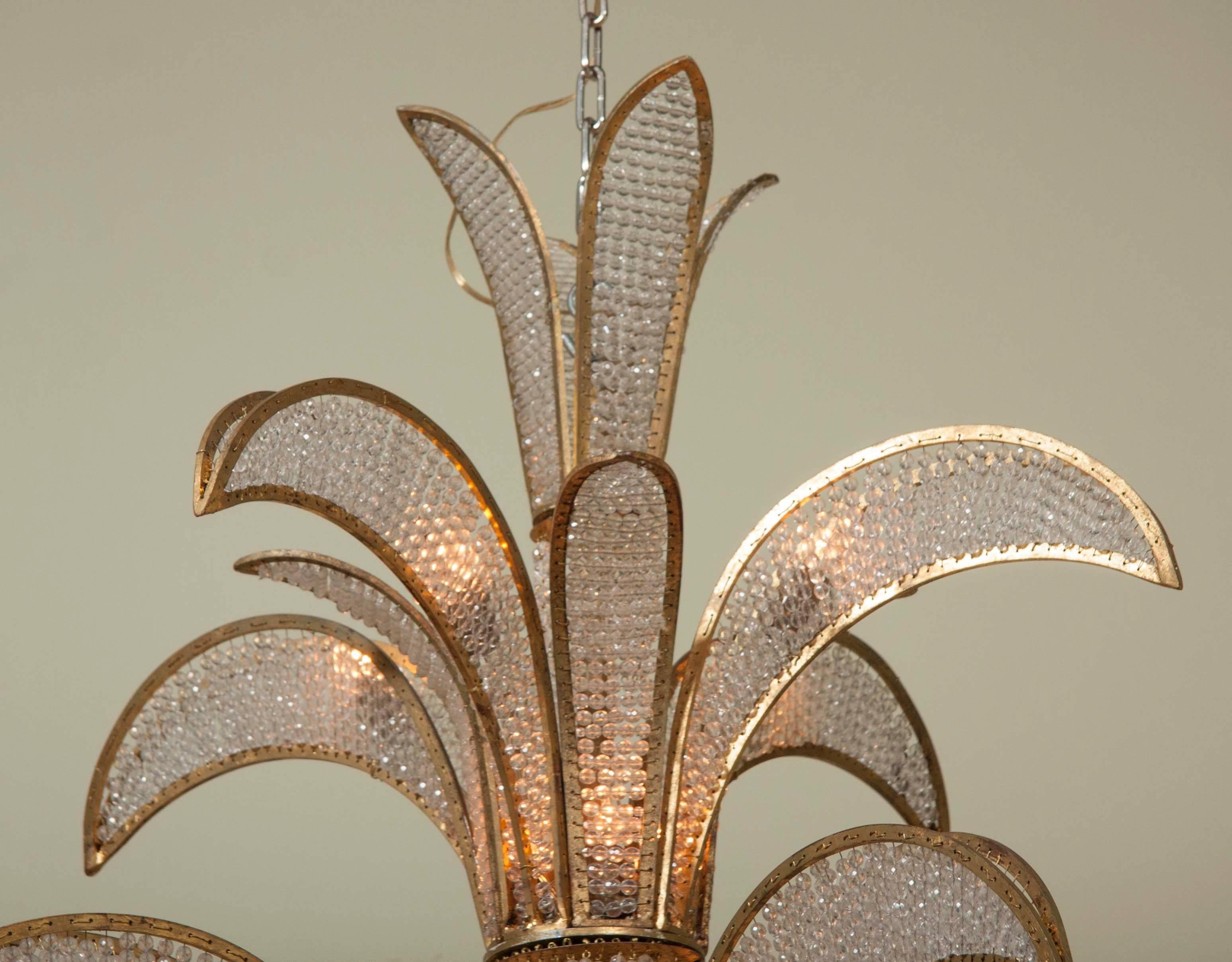 A striking wrought iron gilt metal and crystal bead chandelier in the form of palm fronds. Designed in the manner of Bagues and marketed by Newell.