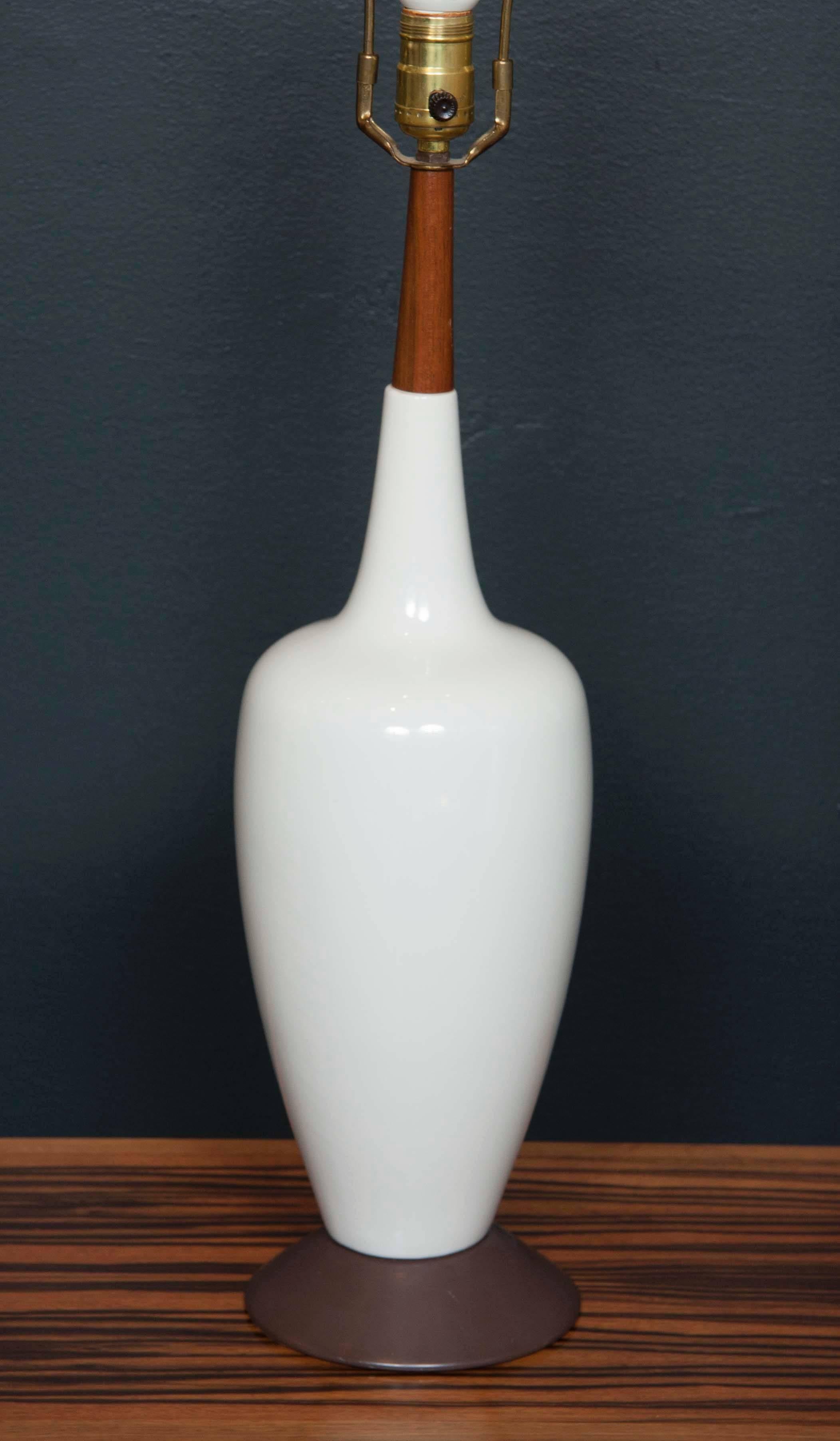 A  Danish Mid-Century table lamp composed of metal base, white ceramic body and slender teak neck.