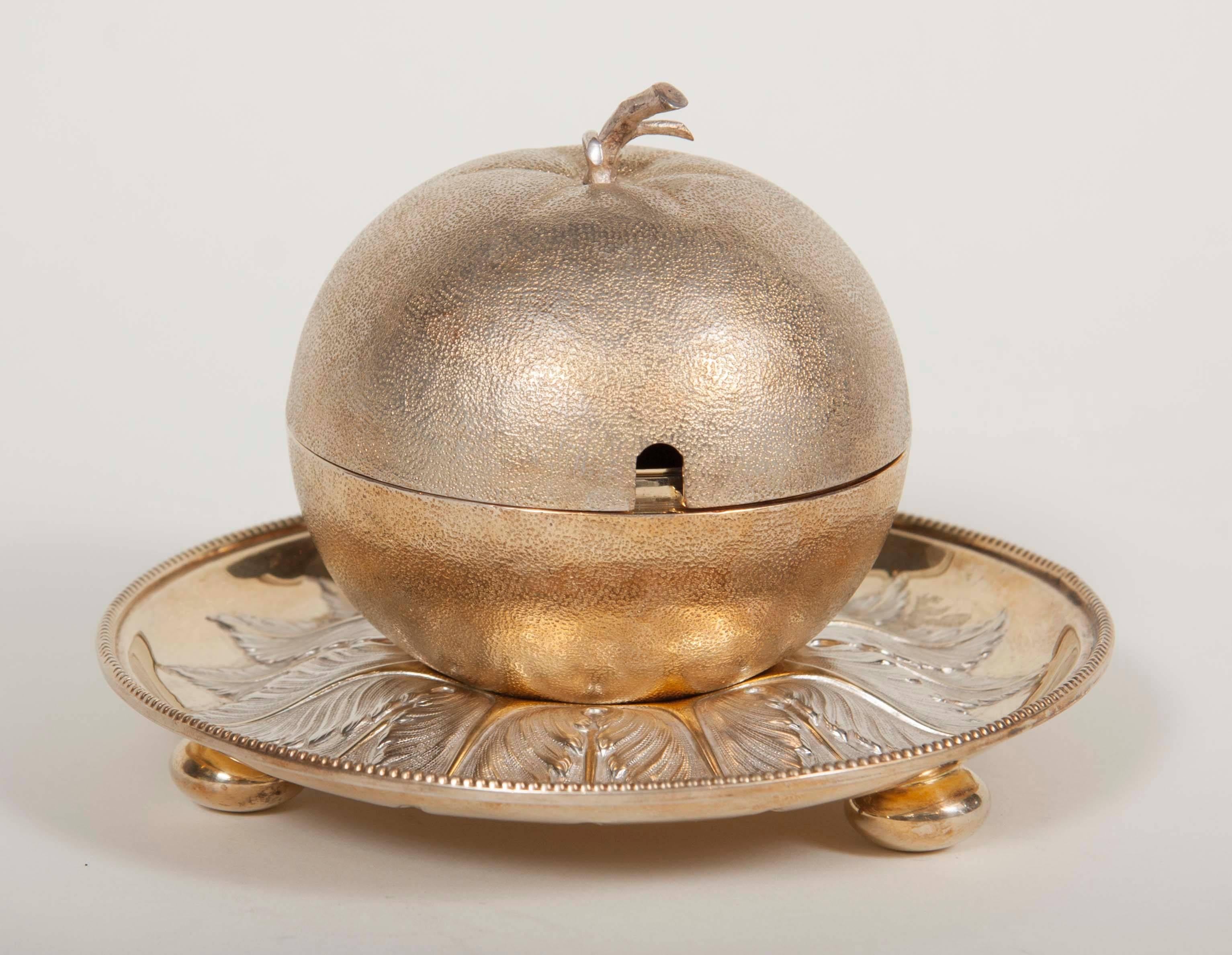 A marmalade jar in the form of a stemmed orange. Gilt silver plate by Fenton Brothers, Sheffield. Supported on a fitted saucer.
