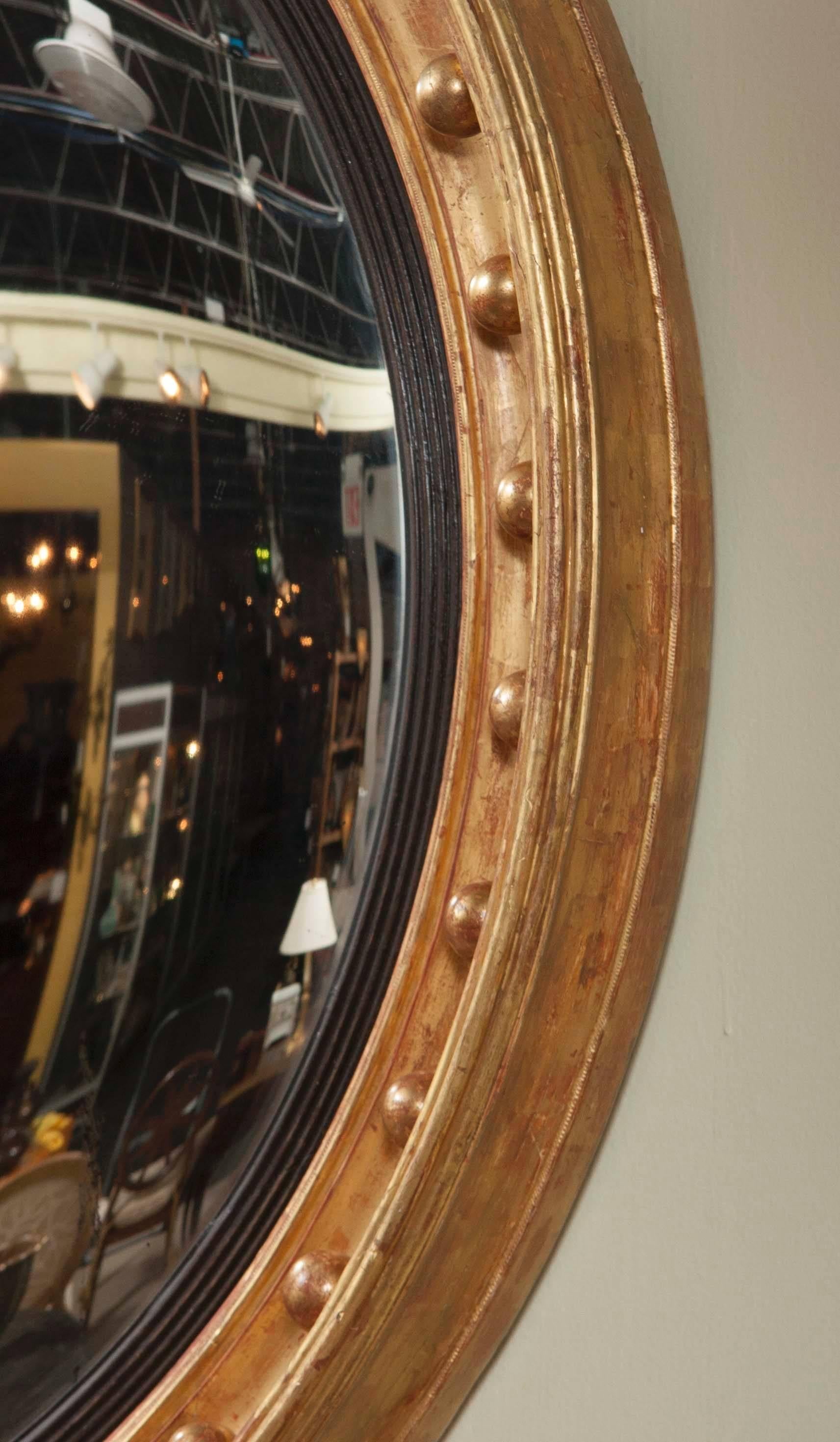 A statement quality, monumental Regency period Bullseye convex mirror with giltwood and parcel ebonized frame.