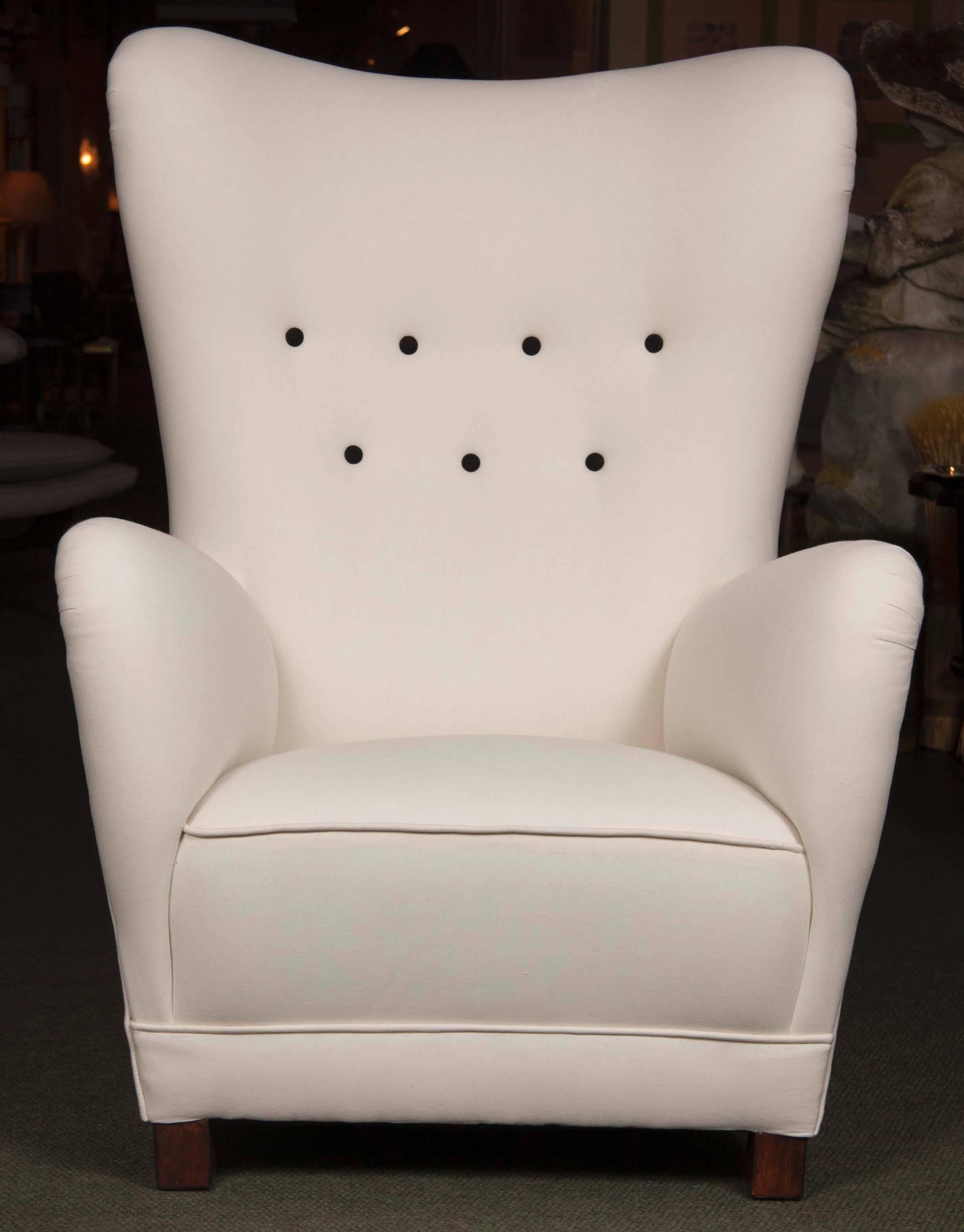 Wing chair attributed to Fritz Hansen upholstered in muslin with black buttons.
