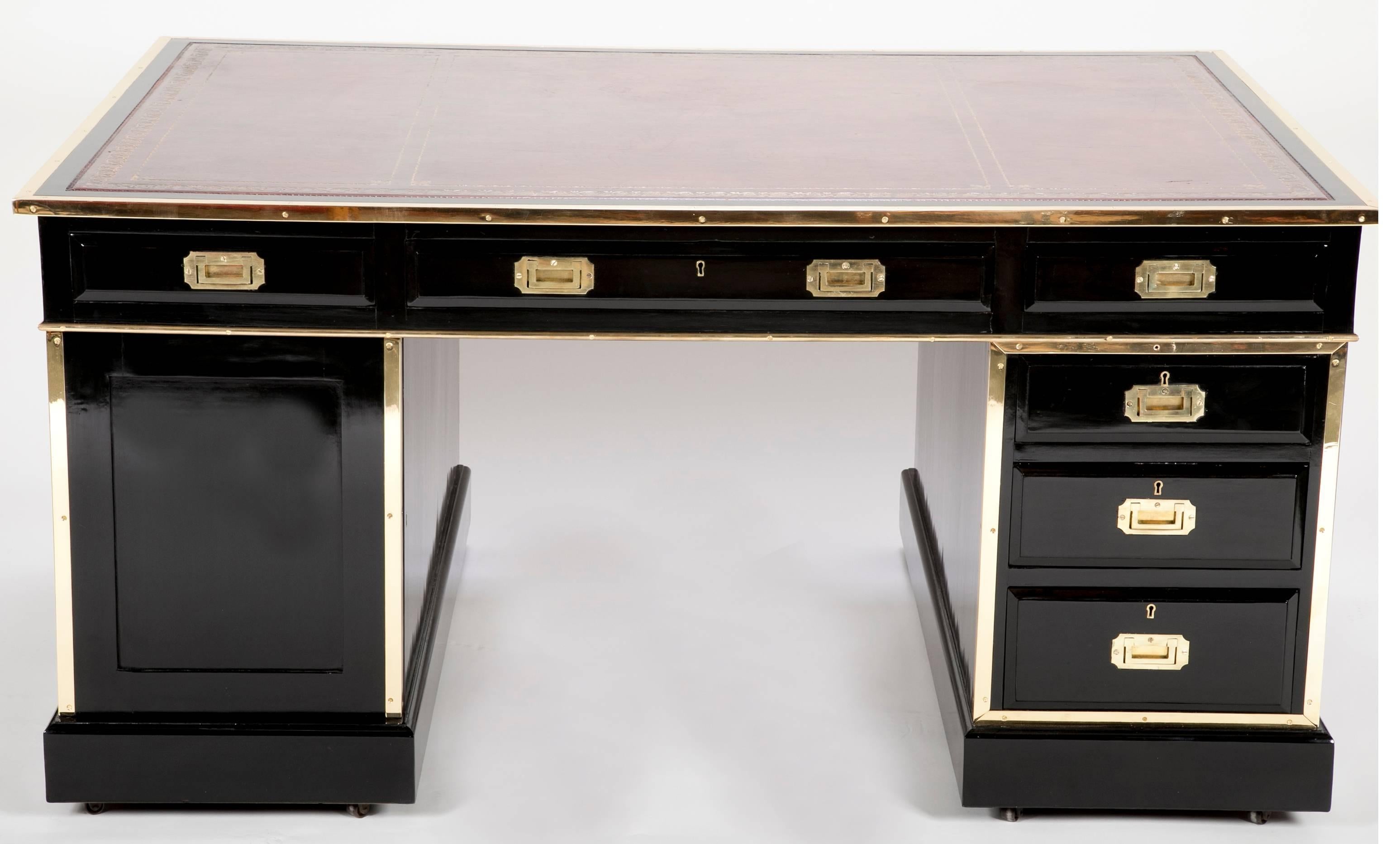 An English black lacquer and brass mounted campaign partners desk with leather top.     The locks are marked Hobbs & Co. 