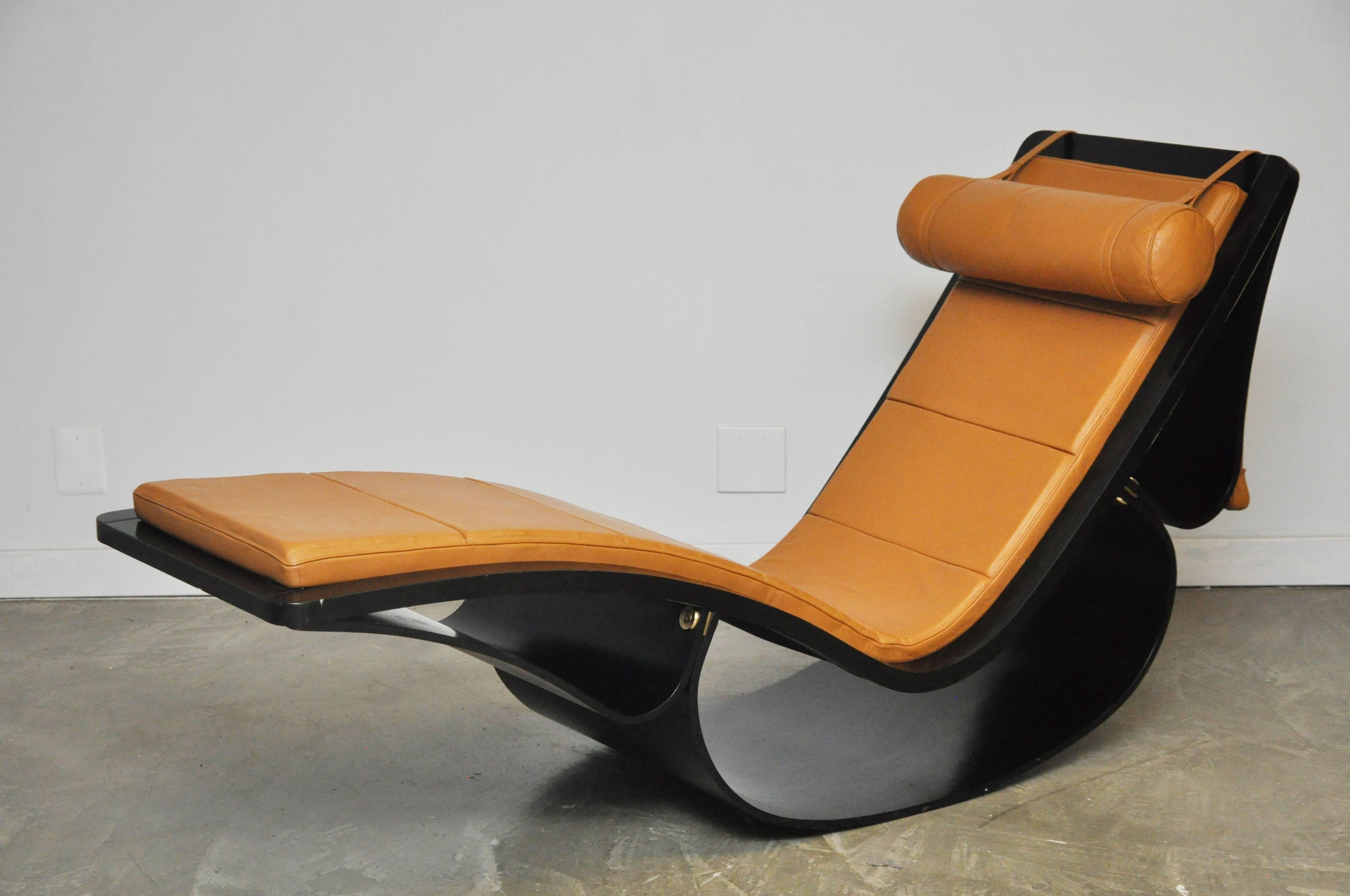 Sculptural rocking chaise longue in black painted laminated wood frame, brass fittings, and original tan leather upholstery with adjustable counterbalanced headrest. Designed in 1978 by famed Brazilian architect, Oscar Niemeyer, and manufactured by