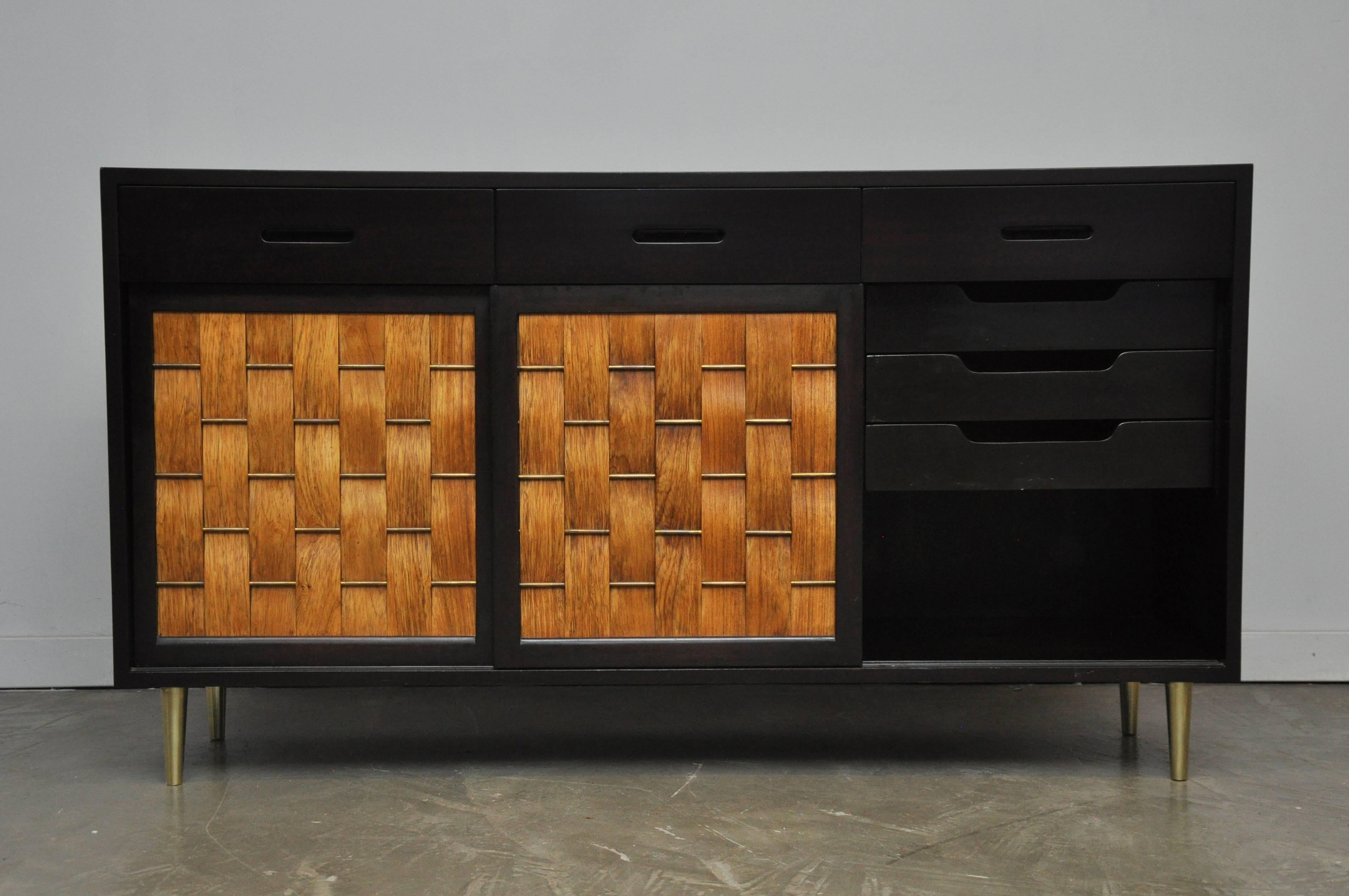 Three-door credenza designed by Edward Wormley for Dunbar. Model #5668. Espresso tone mahogany case with brass details on doors and legs. Three woven bleached rosewood sliding doors. Beautiful restored condition.