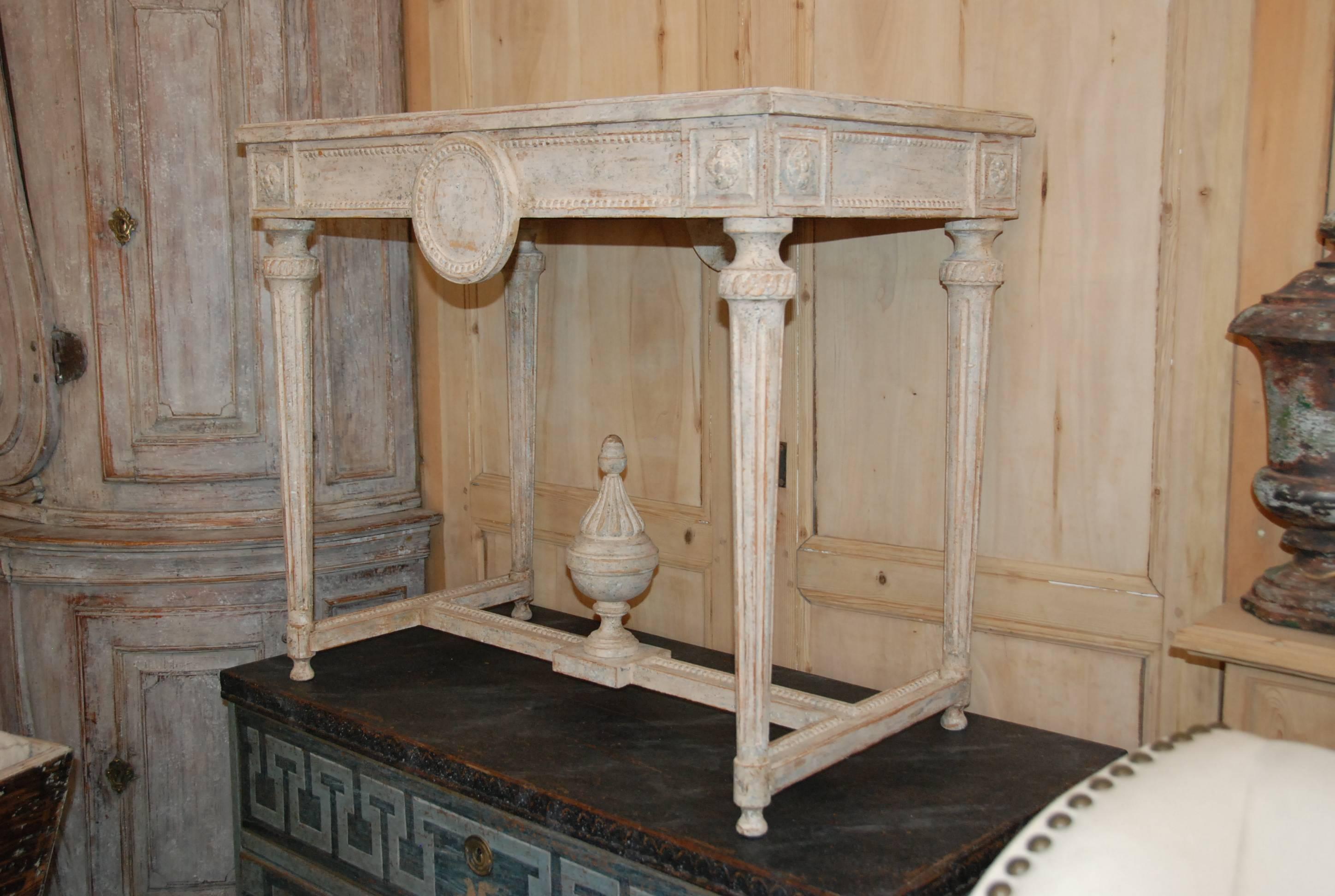 19th century Swedish console table with lovely carved apron over tapered fluted legs. Soft cream or white color. Carving extends all the way around the table making it an excellent centre table as well.