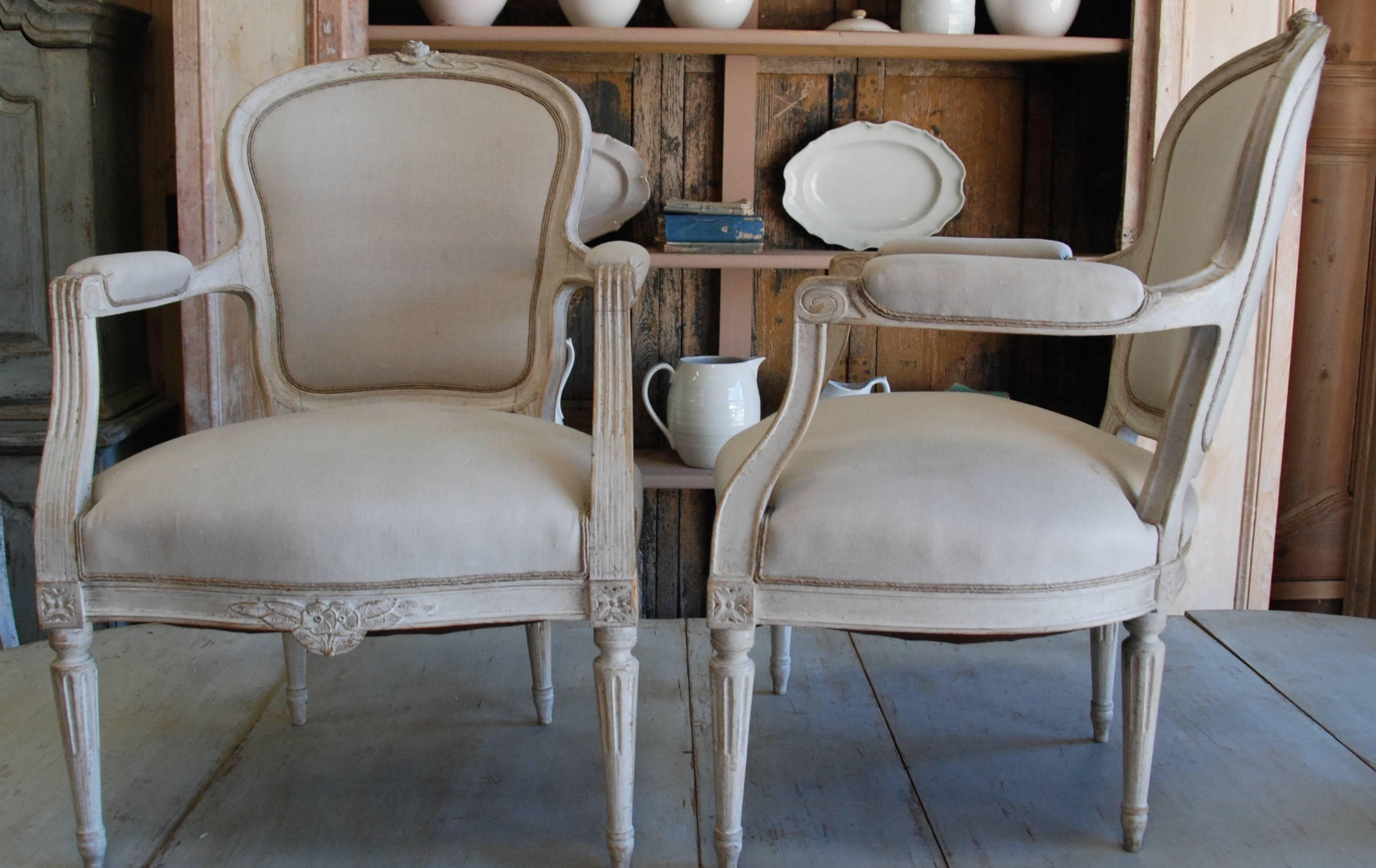 Pair of 19th century Swedish bergere chairs newly restored. Lovely cream color with carved legs and apron over fluted tapered legs.