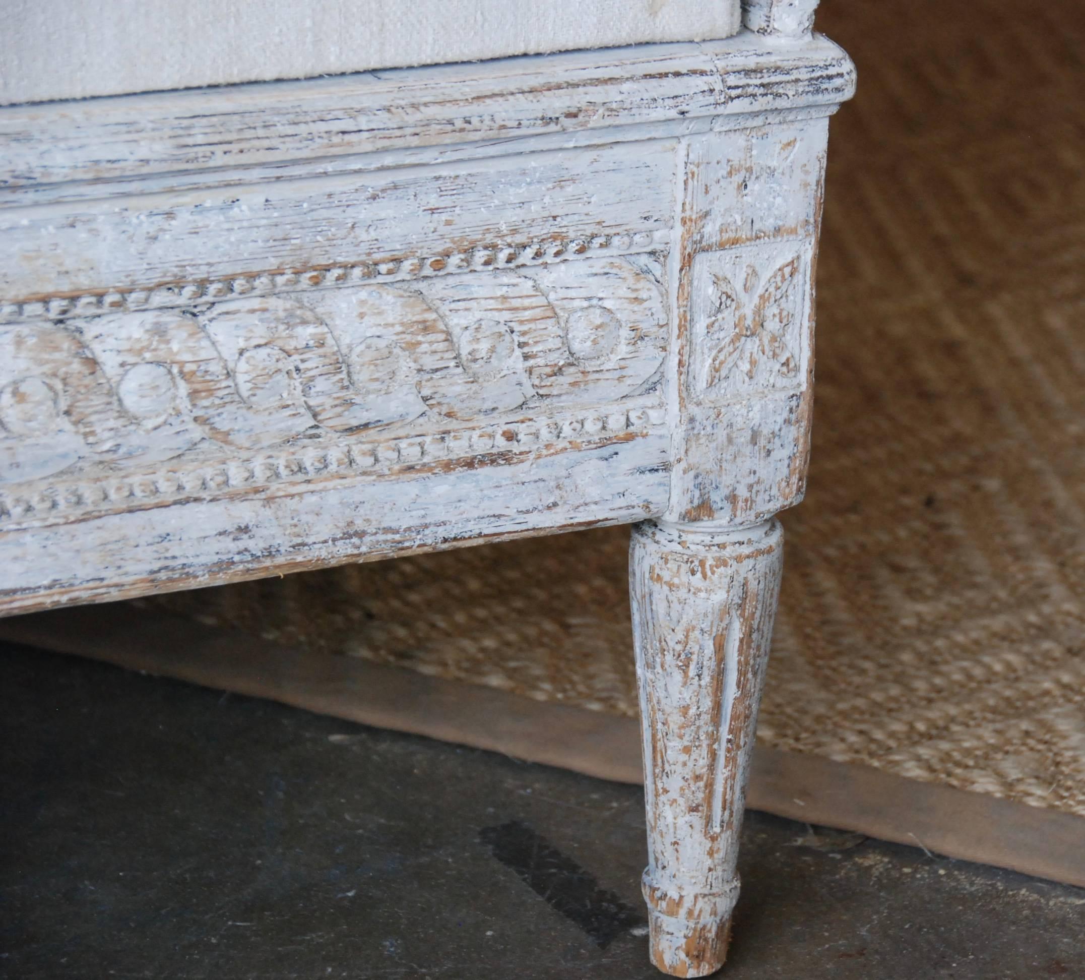 18th century Swedish period Tragsoffa, scraped down to original lovely cream or white color. Beautiful carved apron over reeded tapered legs. Upholstered in antique Swedish Hemp. Great size. Stockholm, Sweden.