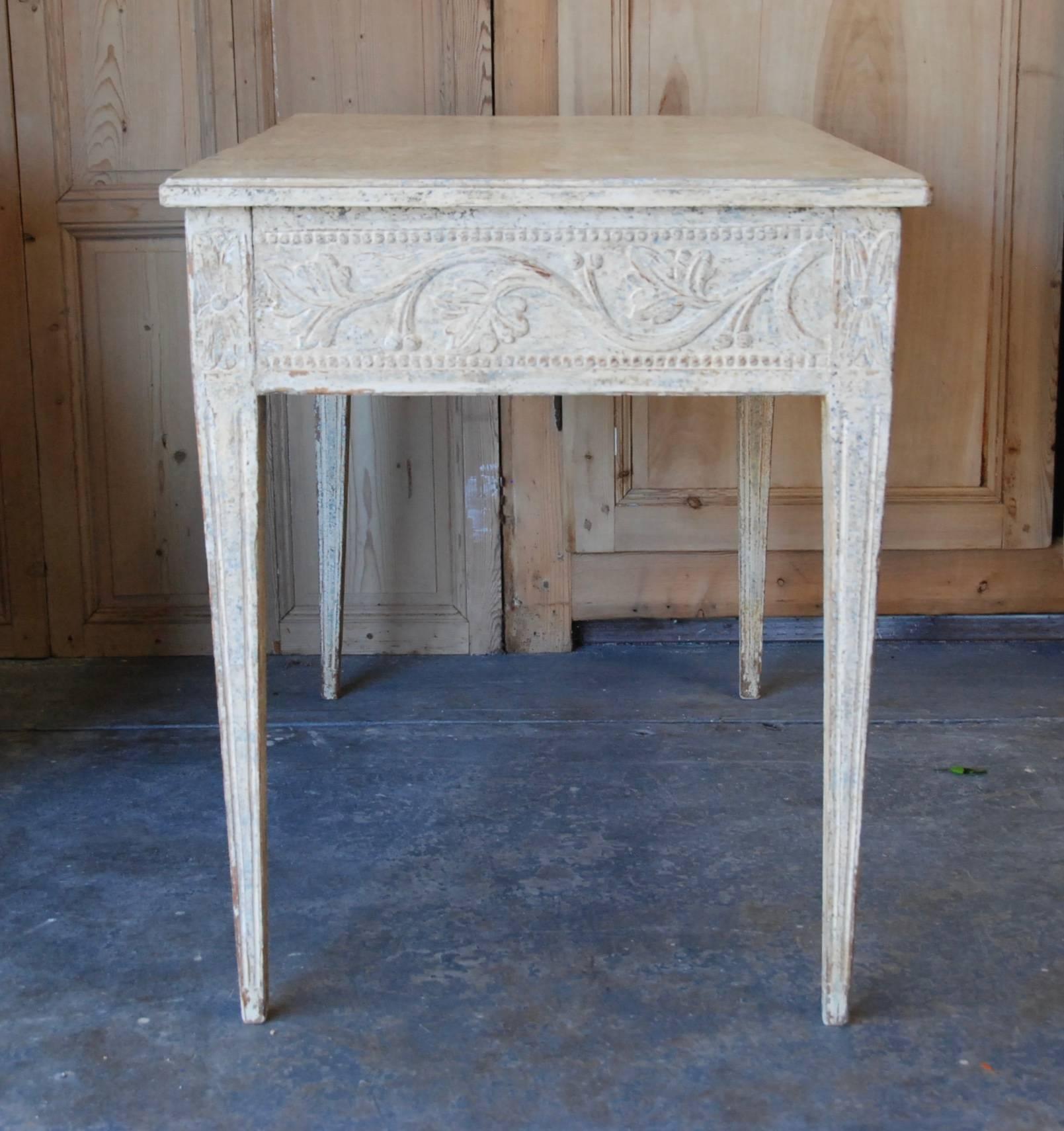 19th century Swedish console table with lovely carved apron and tapered fluted legs. The beautiful carving extends all around the table in a soft Swedish cream or white color.