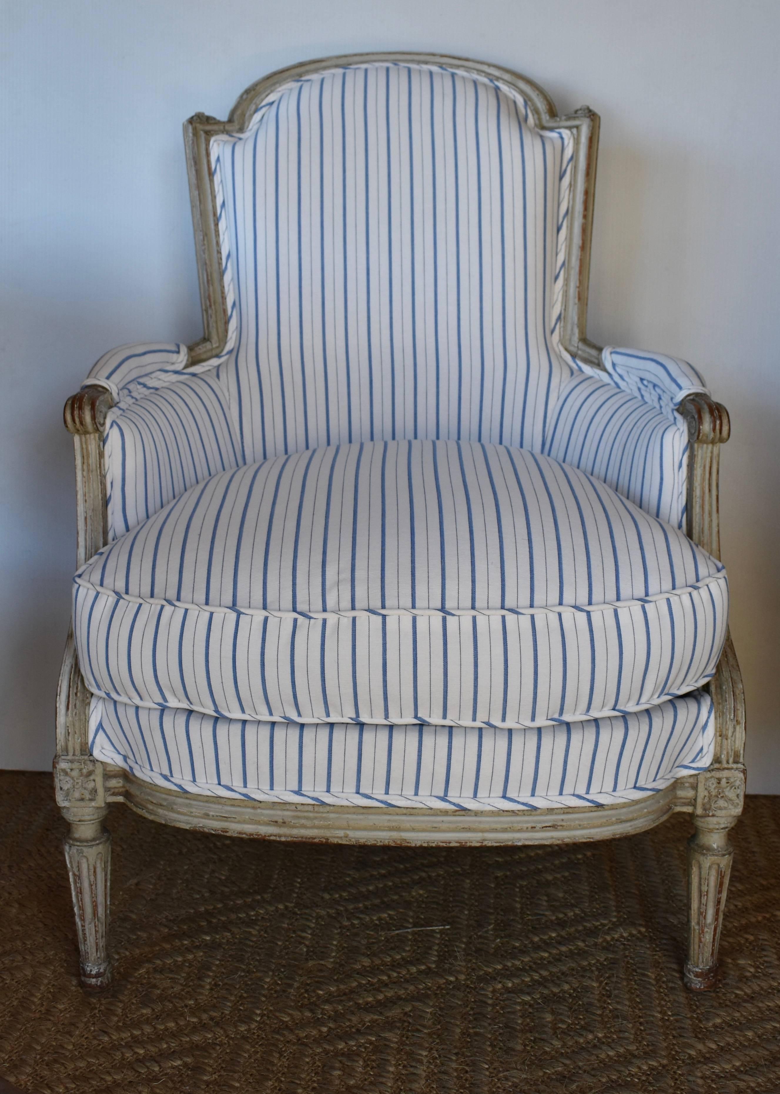 Beautiful 19th century painted French Bergere newly upholstered in blue and white stripe. Lovely carved arms and tapered legs. Great aged patina. Very comfortable with down filled cushion.