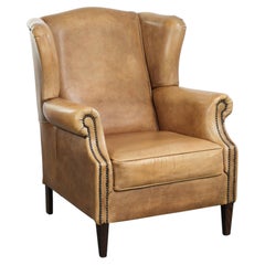 Comoda poltrona con schienale ad ali in pelle di vacchetta, dal look inglese senza tempo
