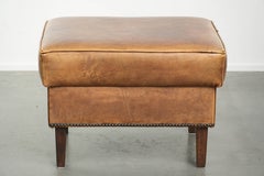 Pouf in pelle di vacchetta con una splendida patina e rifinito con chiodini decorativi
