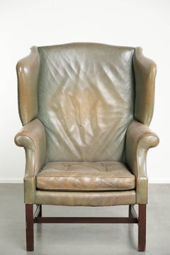 Old cow leather wingback armchair in English style with beautiful patina