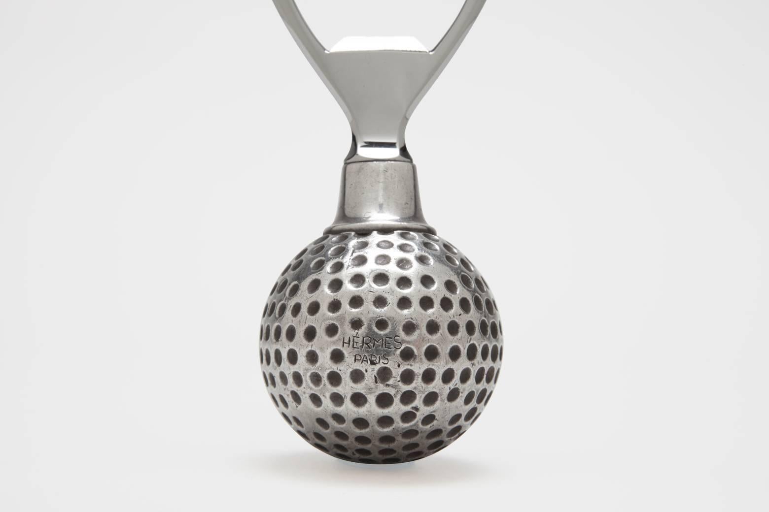 A stainless steel and silver plated bottle opener, with the handle in the form of a fully three dimensional golf ball. This is a fantastic bar piece, and quite rare. Wonderful in the hand, very sturdy and a great conversational piece. It is made in