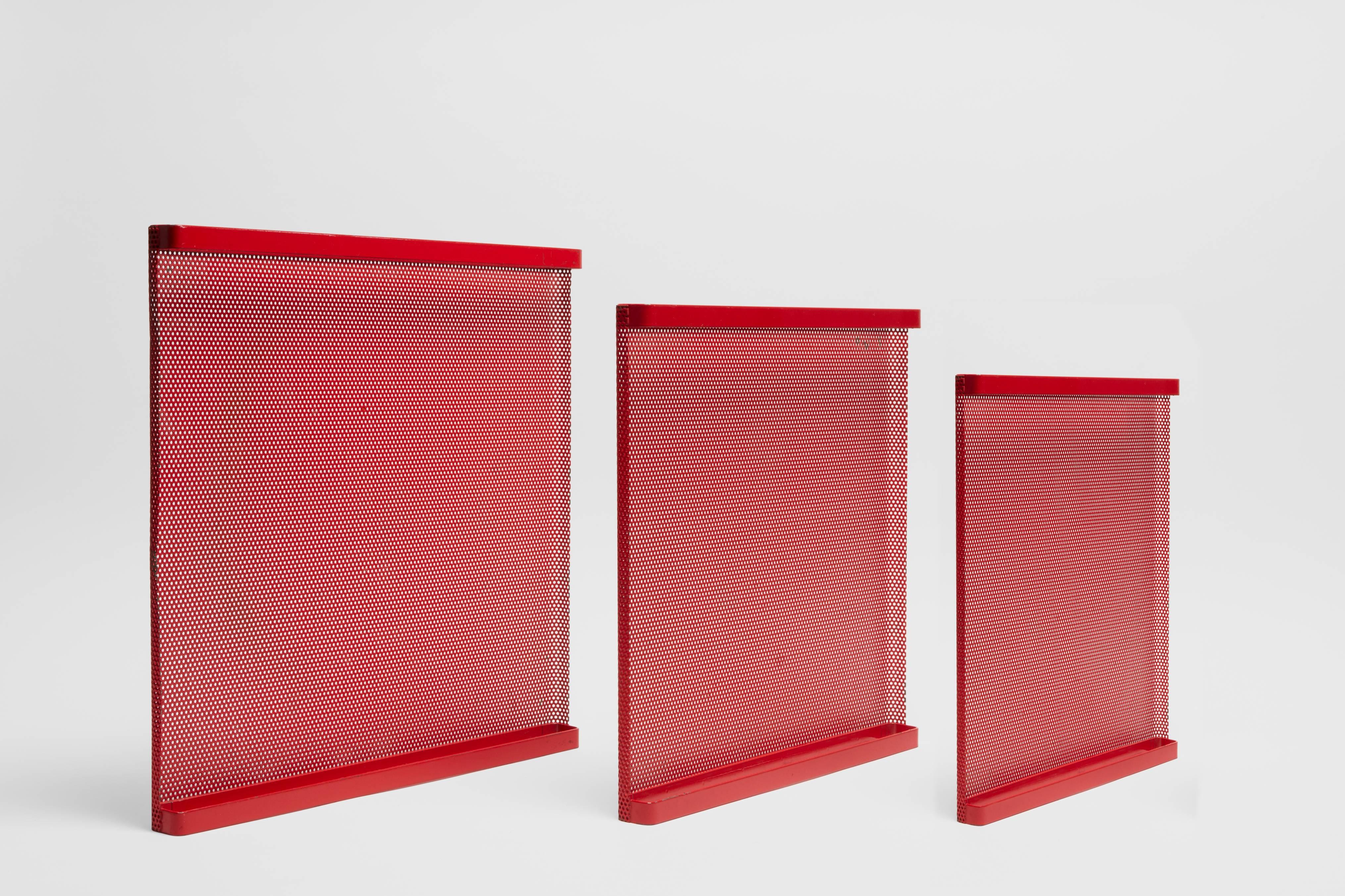 A set of three red perforated metal nesting trays. This set is made by esteemed French designer and artist Mathieu Matégot. These nesting trays are executed in Mategot's preferred medium of steel, which he was famous for using in varied modalities