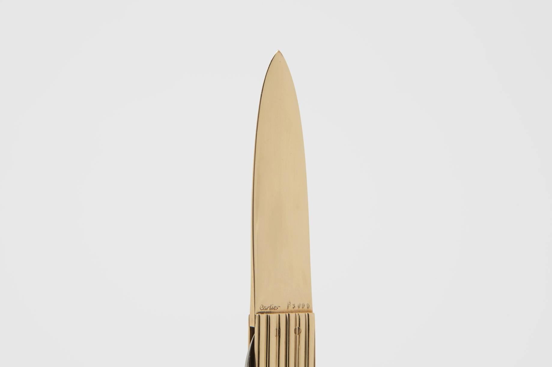 A solid gold Cartier signed letter opener with stainless steel retractable bladed pocket knife set into the handle. The piece is very finely made, with a comfortable and easy to grip reeded handle, a well designed blade to easily slide into