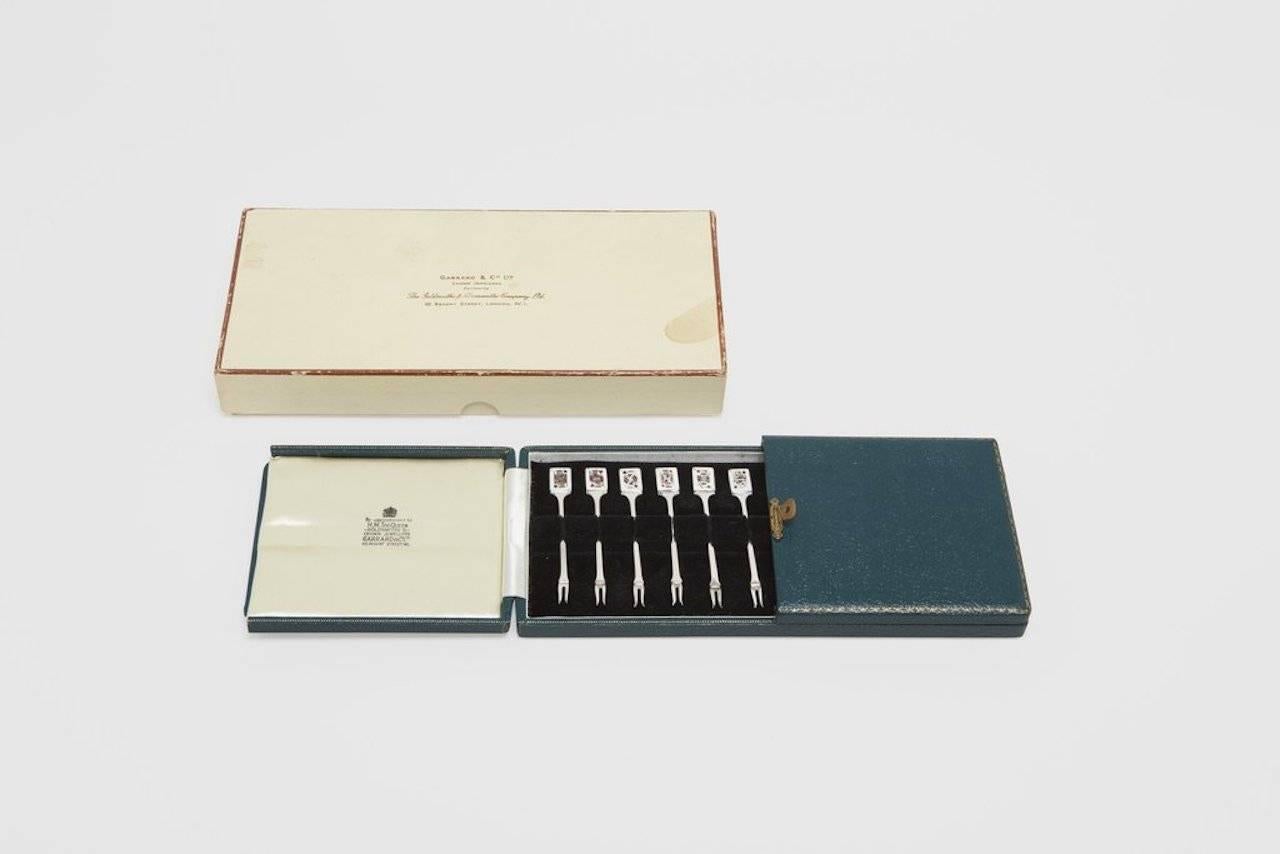 A set of 12 sterling silver and vitreous enamel cocktail picks featuring the full set of Royal Court cards for each suit in the deck. These exquisite picks were made by one of the finest silversmiths to ever work; Garrard & Co.. George Wickes