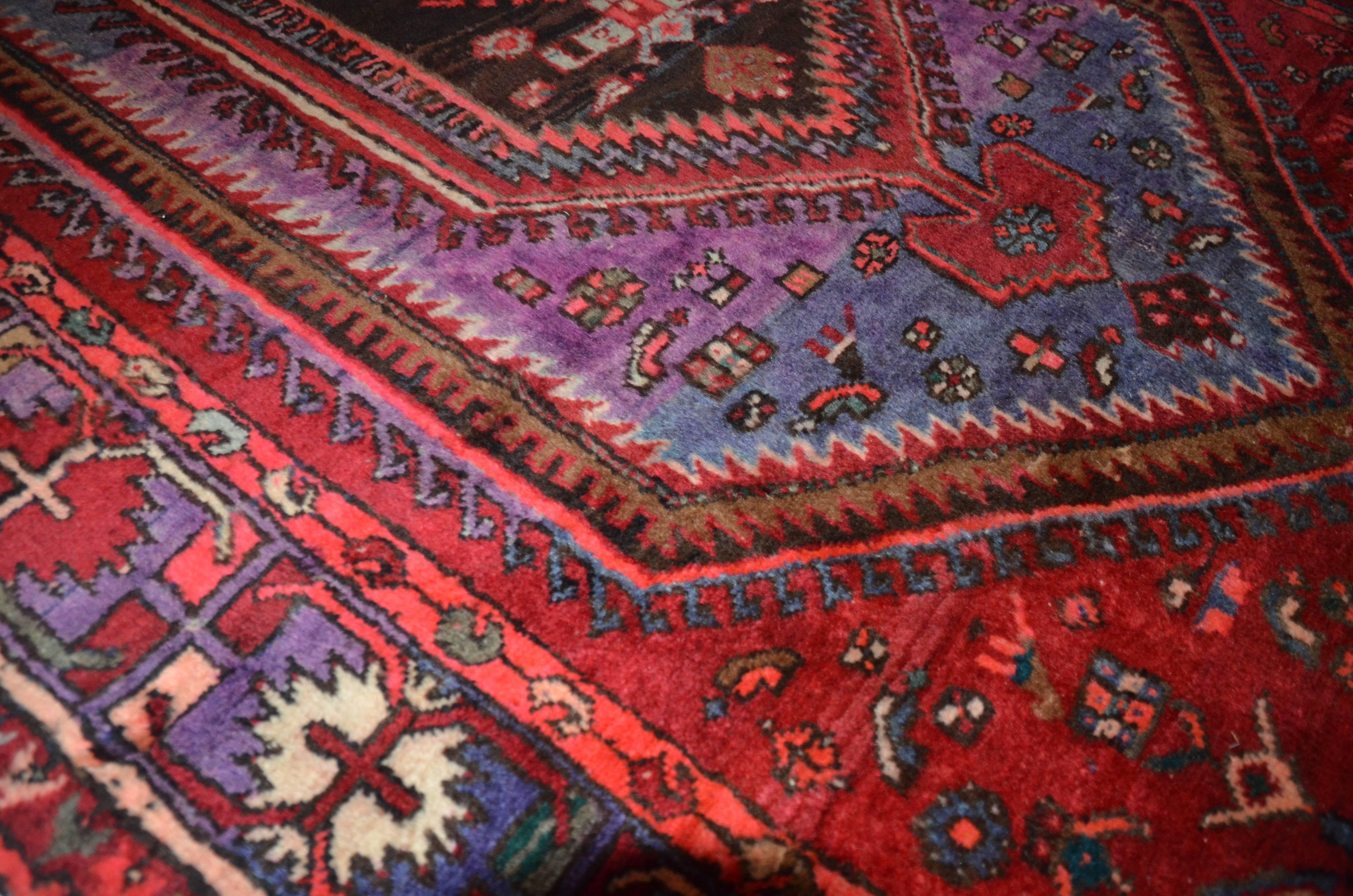 Rug measures 4.5' x 7' foot and features a red ground with purple and blue accents. Nice vintage rug with bright coloring.