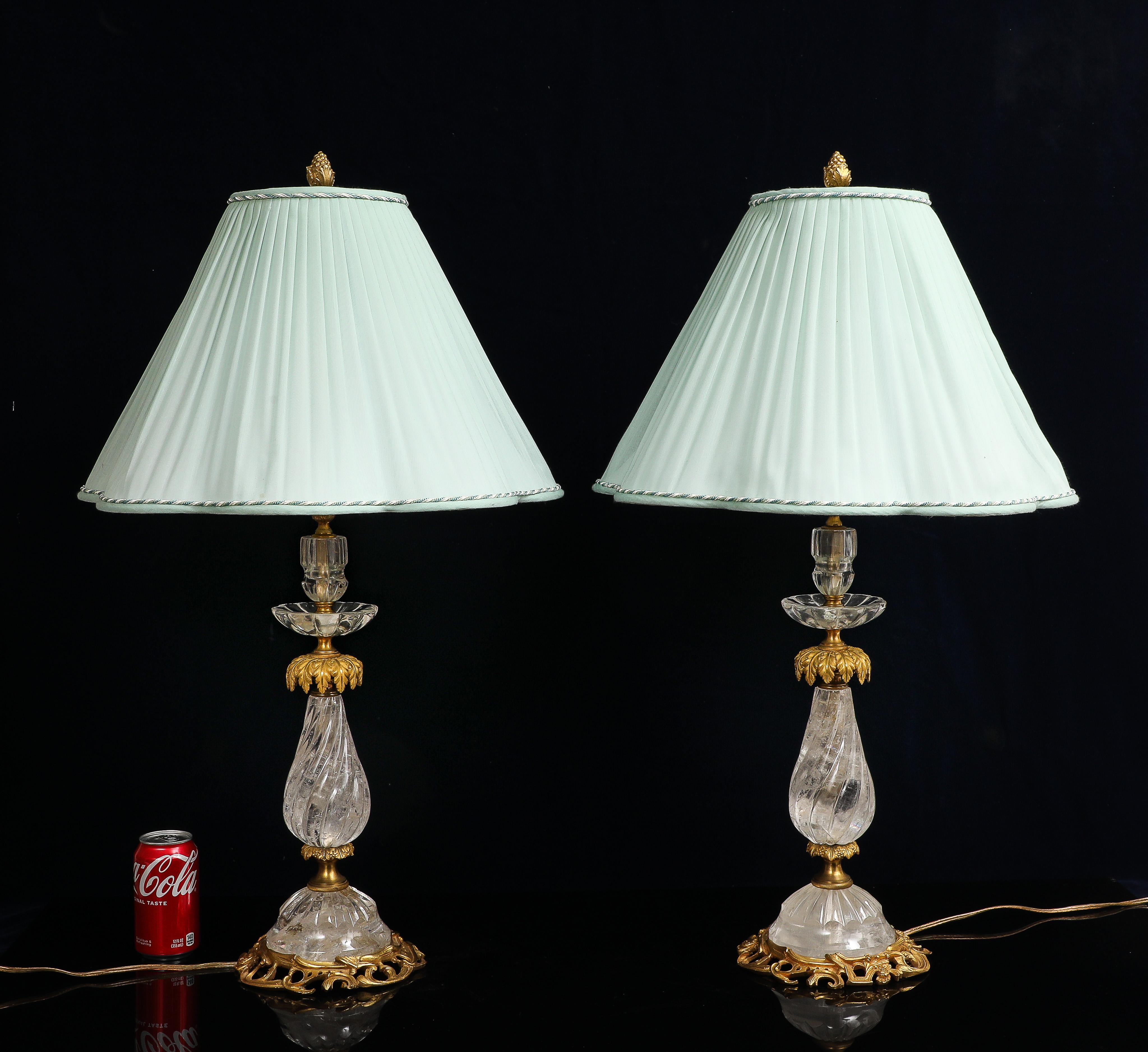 A Pair of Hand-Carved Rock Crystal and Gilt Bronze Table Lamps by E.F. Caldwell & Co., New York, Early 20th Century. Each lamp is constructed using clear rock crystal elements of varying forms, including faceted baluster necks, shallow circular