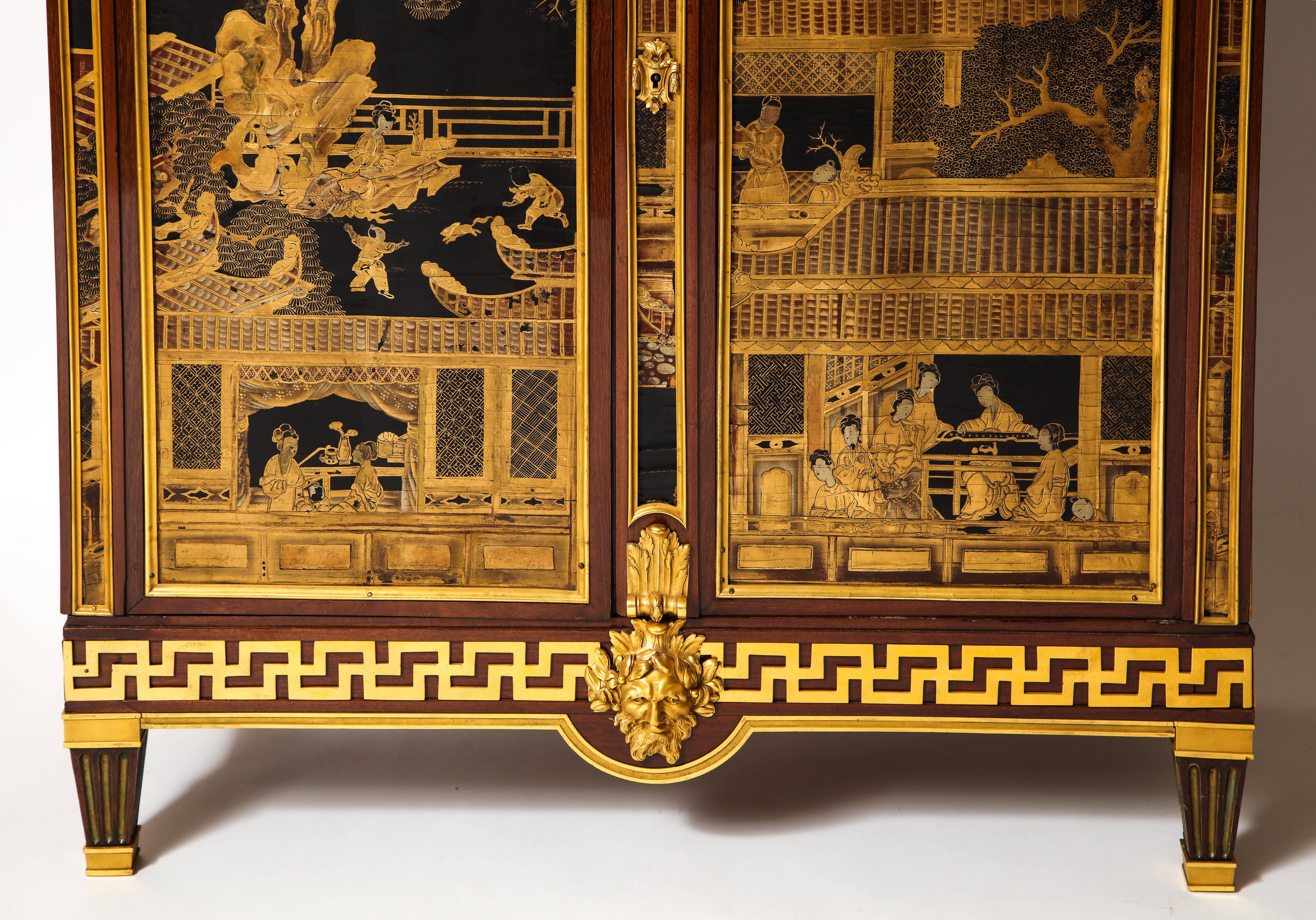 A spectacular antique French Louis XVI style gilt bronze mounted mahogany Chinese lacquered double door cabinet embellished with Chinese gilt decorated lacquered panels depicting chinoiserie scenes and further mounted with fine gilt bronze detail,