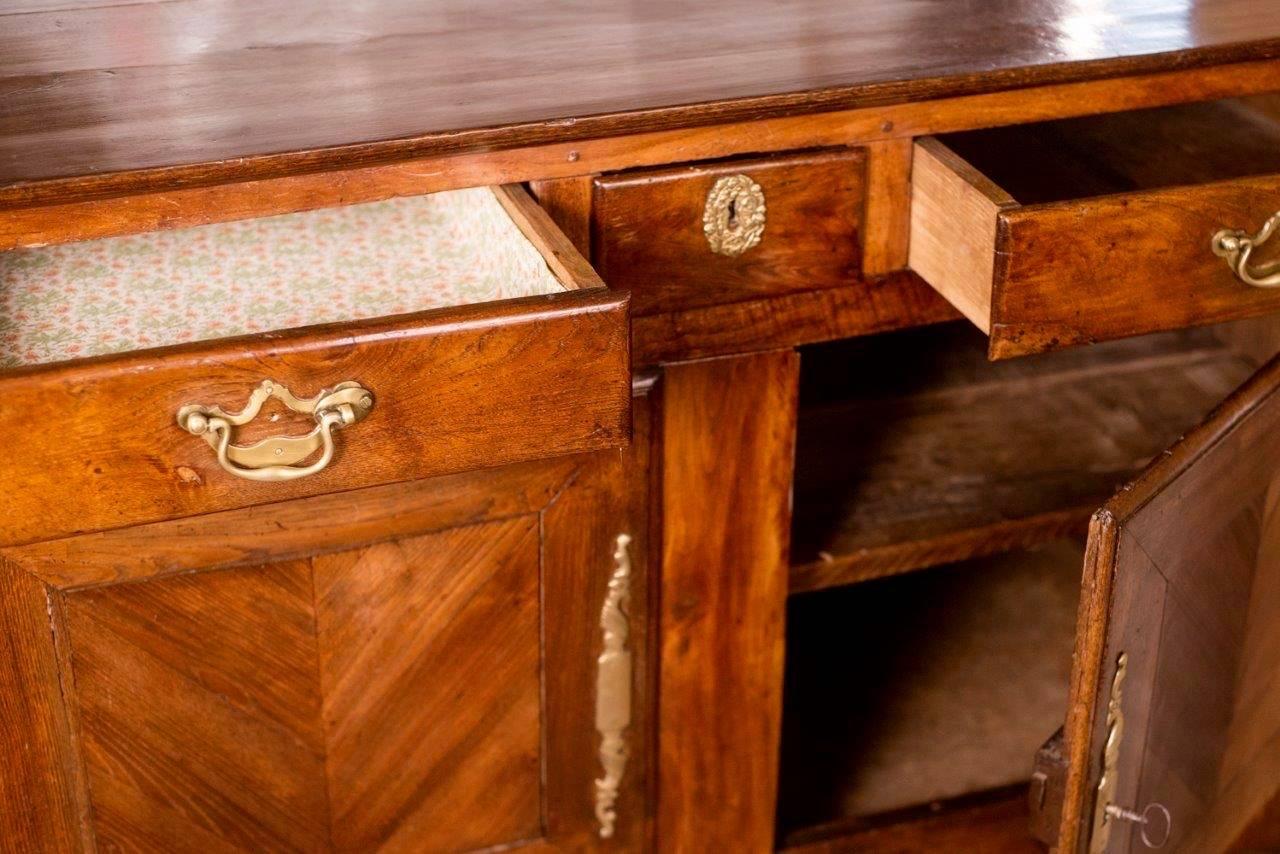 Early 19th century French regional buffet. Made of chestnut, this piece was
hand-hewn in Brittany, circa 1820 and retains the original brass hardware.
There are three top drawers lined with fabric and two doors for storage.
Subtle carvings adorn