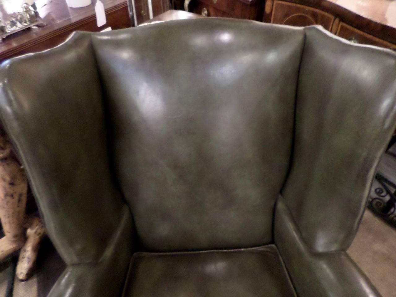 
Vintage Chippendale style wing chair in pale green leather with matching ottoman with brass tack trim. Minor wear on the chair and some cracking on the ottoman, commensurate with age.
The exposed wood frame is mahogany. Both pieces are labeled