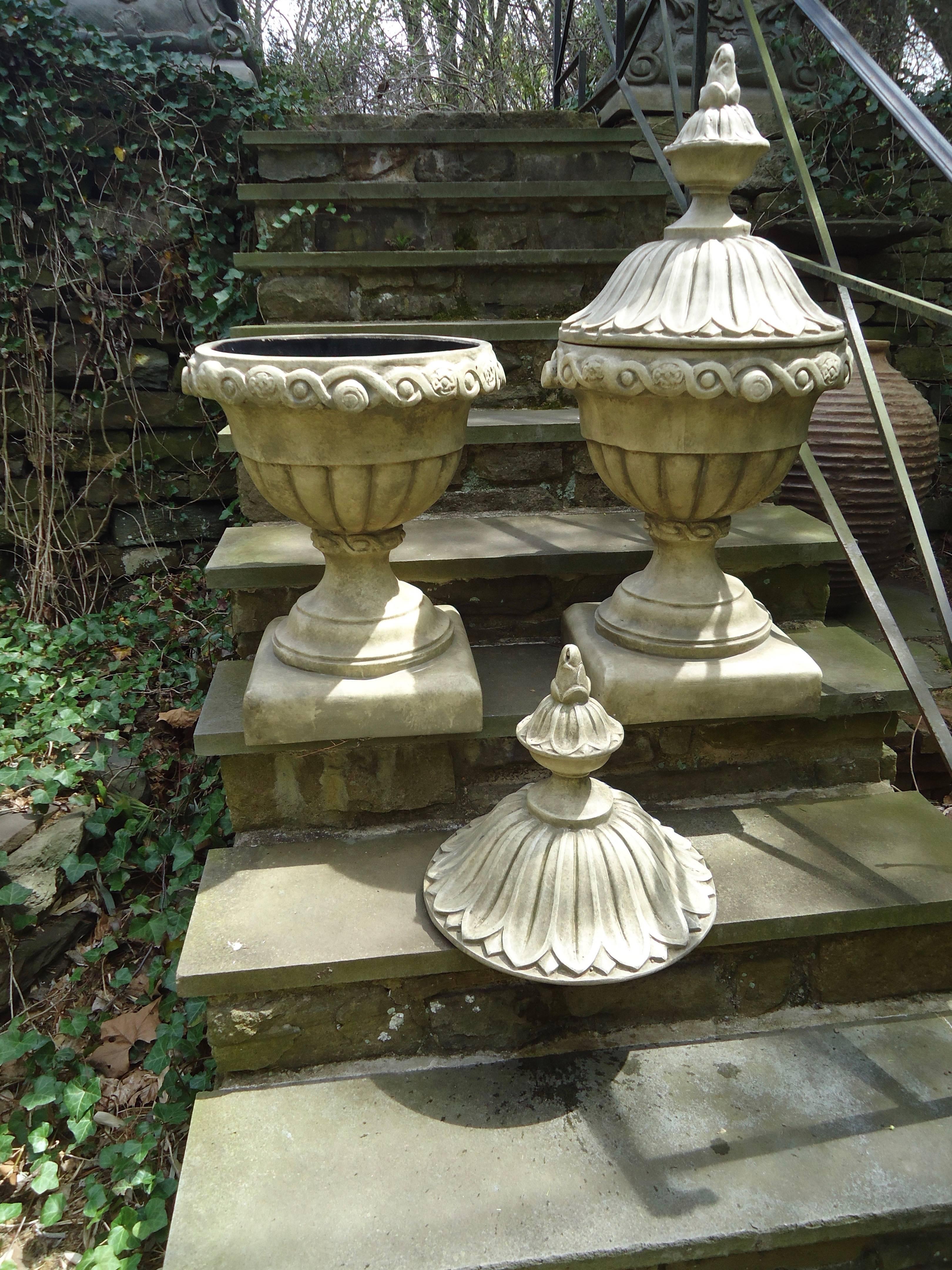 Elegant pair of fiberglass resin urns with lids that are hand cast from the original French antique urns, having intricate details and a hand-painted faux limestone finish. This high quality medium is impervious to weather, durable and maintenance
