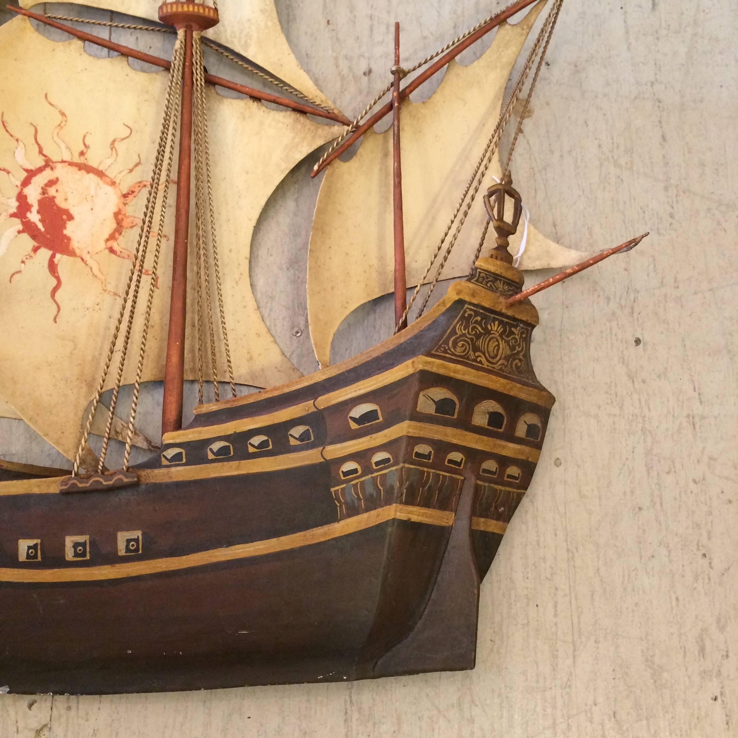 Full of nautical charm, an iron and tole painted wall sculpture of a multi sailed vessel with the moon, stars, flags and meticulous details.