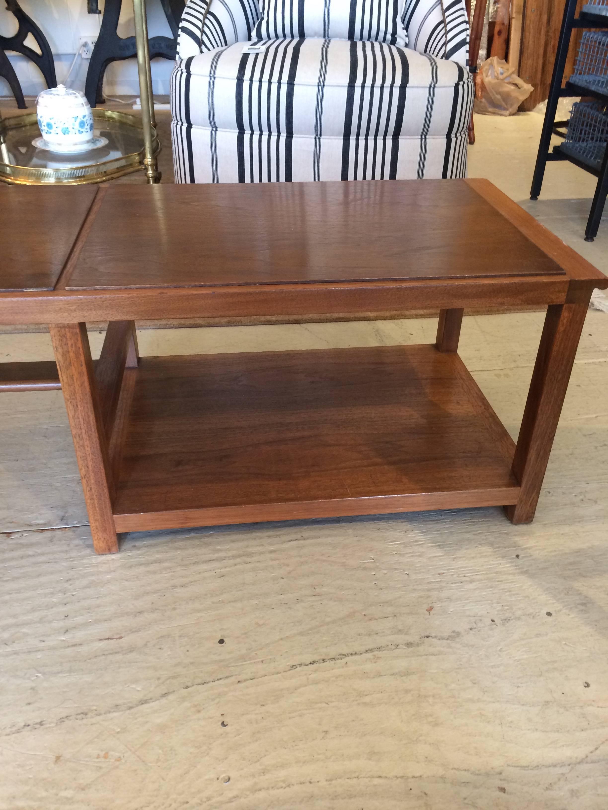 Unusual long rectangular very sophisticated asymmetrical two-tone walnut coffee table having 1/3 of the coffee table with a second underneath shelf, while the rest is airy with a single stretcher bar. Dunbar label underside.

SC