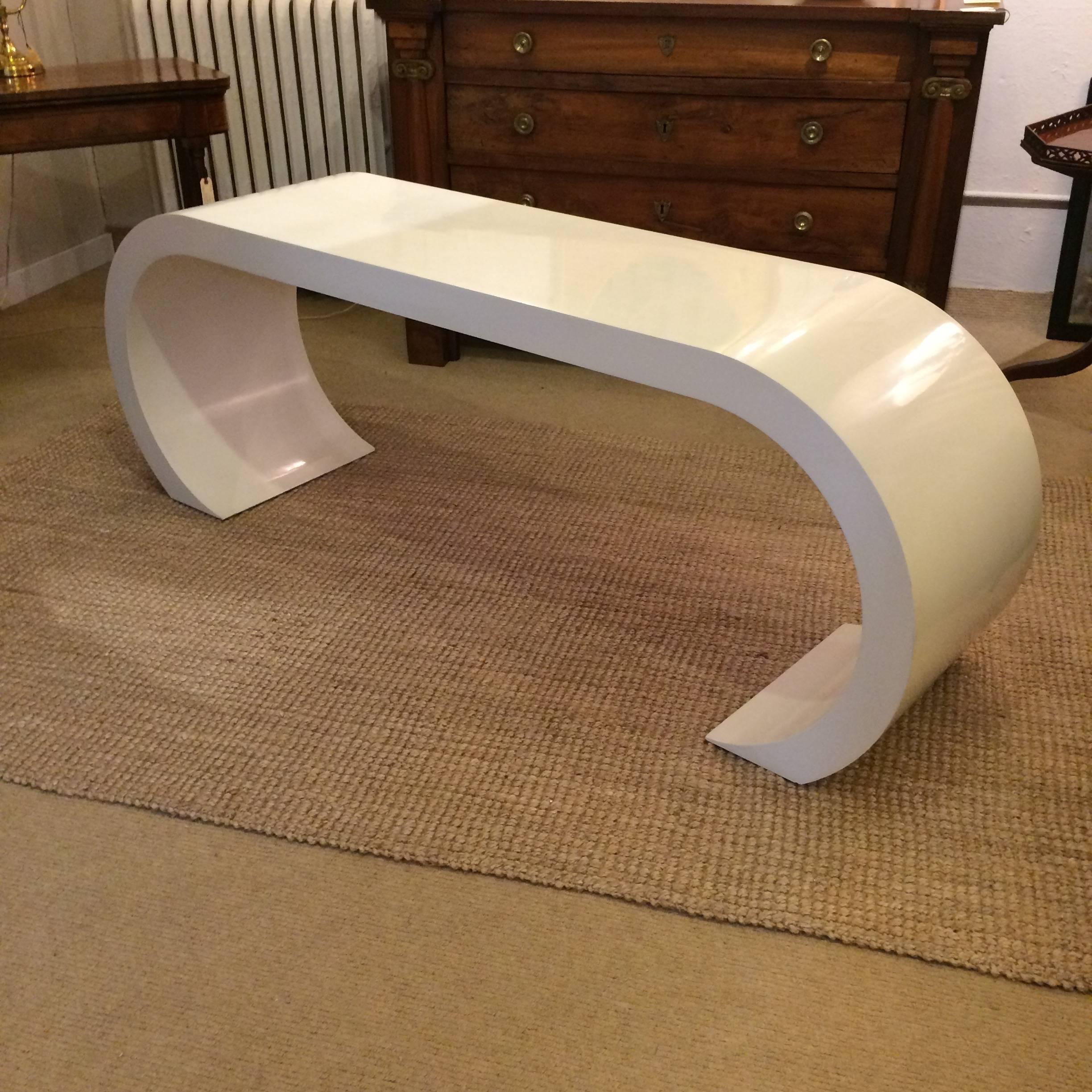 Glamorous console table in a Classic Mid-Century Modern Karl Springer style waterfall shape, made of glossy white laquered wood.