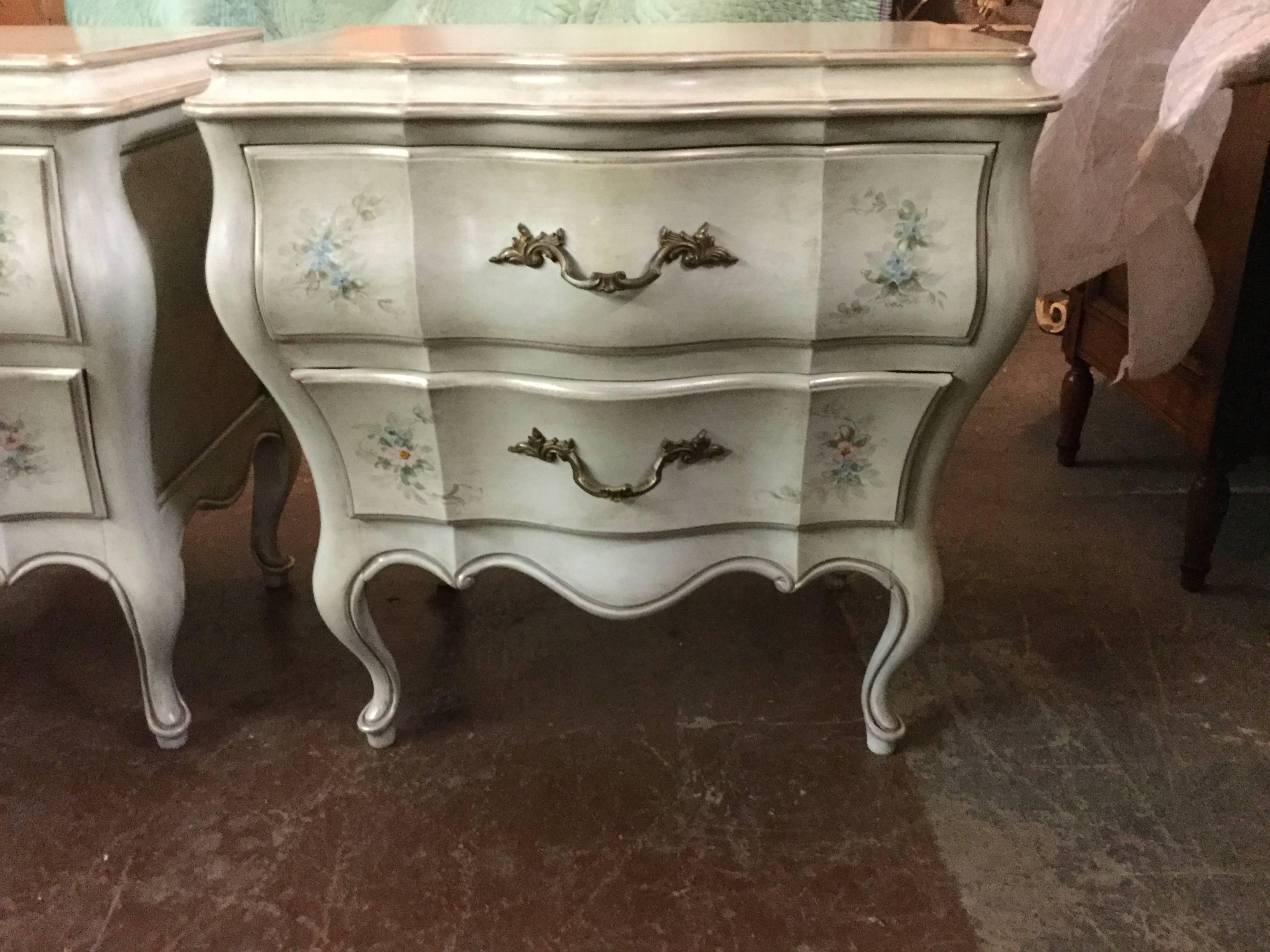 Hand-painted matching bombé chests. Custom painted in a neutral off-white with delicate floral motifs with silver-leaf accents throughout, including front of drawers and all edges.

Pair of chests: 25 wide x 18 deep x 26 tall.