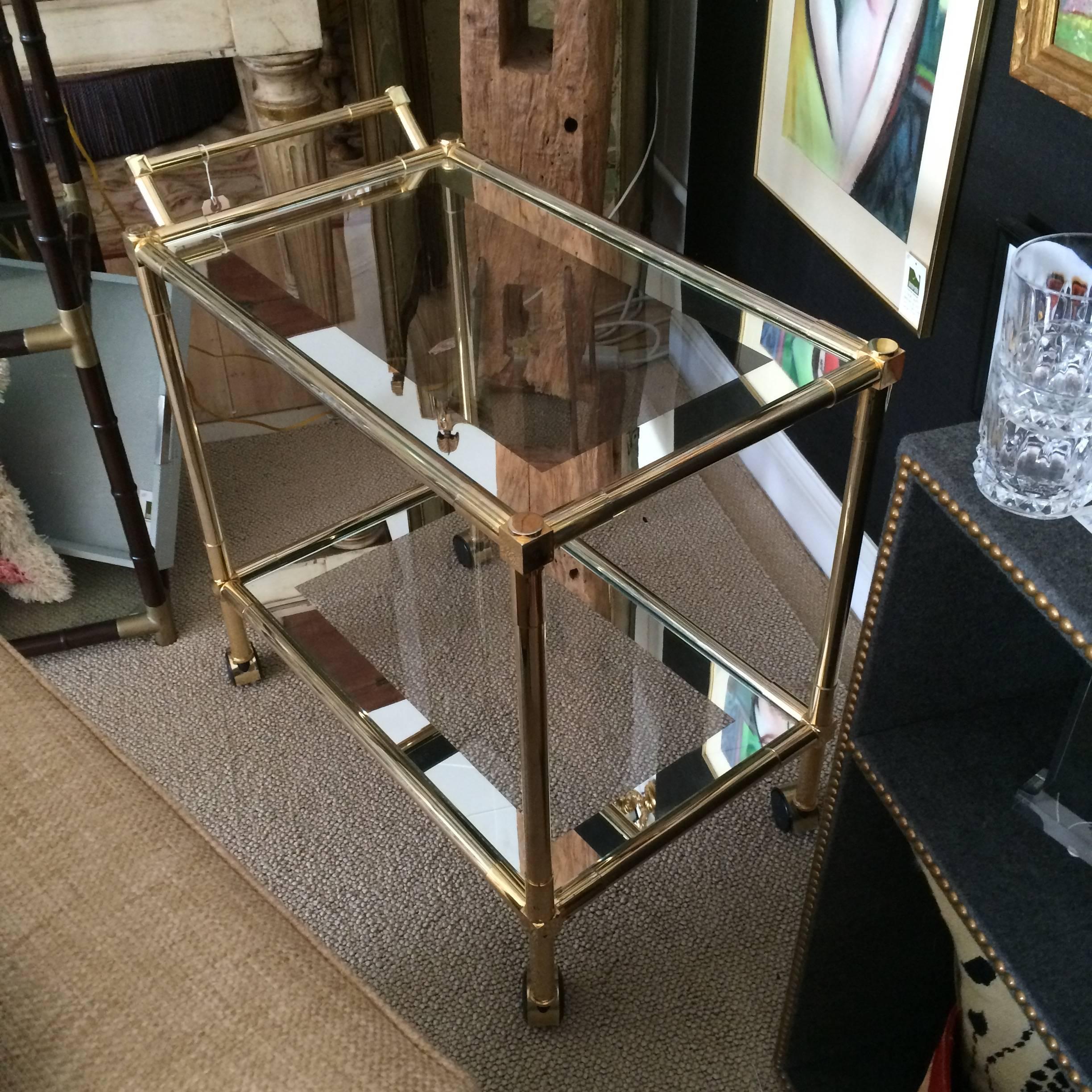 Elegant Mid-Century Modern bar cart with brass structure having geometric cube details on the handle and corners and two glass tiers that are mirrored around the edges for a glamorous look.