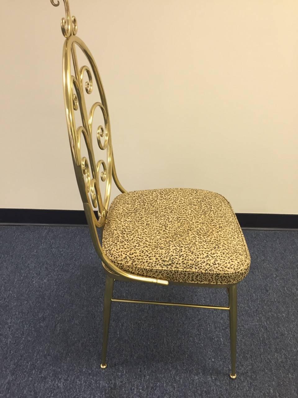 Four very chic Italian polished brass dining chairs with a wonderful whimsical curlicue motiffe. Seats are upholstered in the original faux leopard cotton.