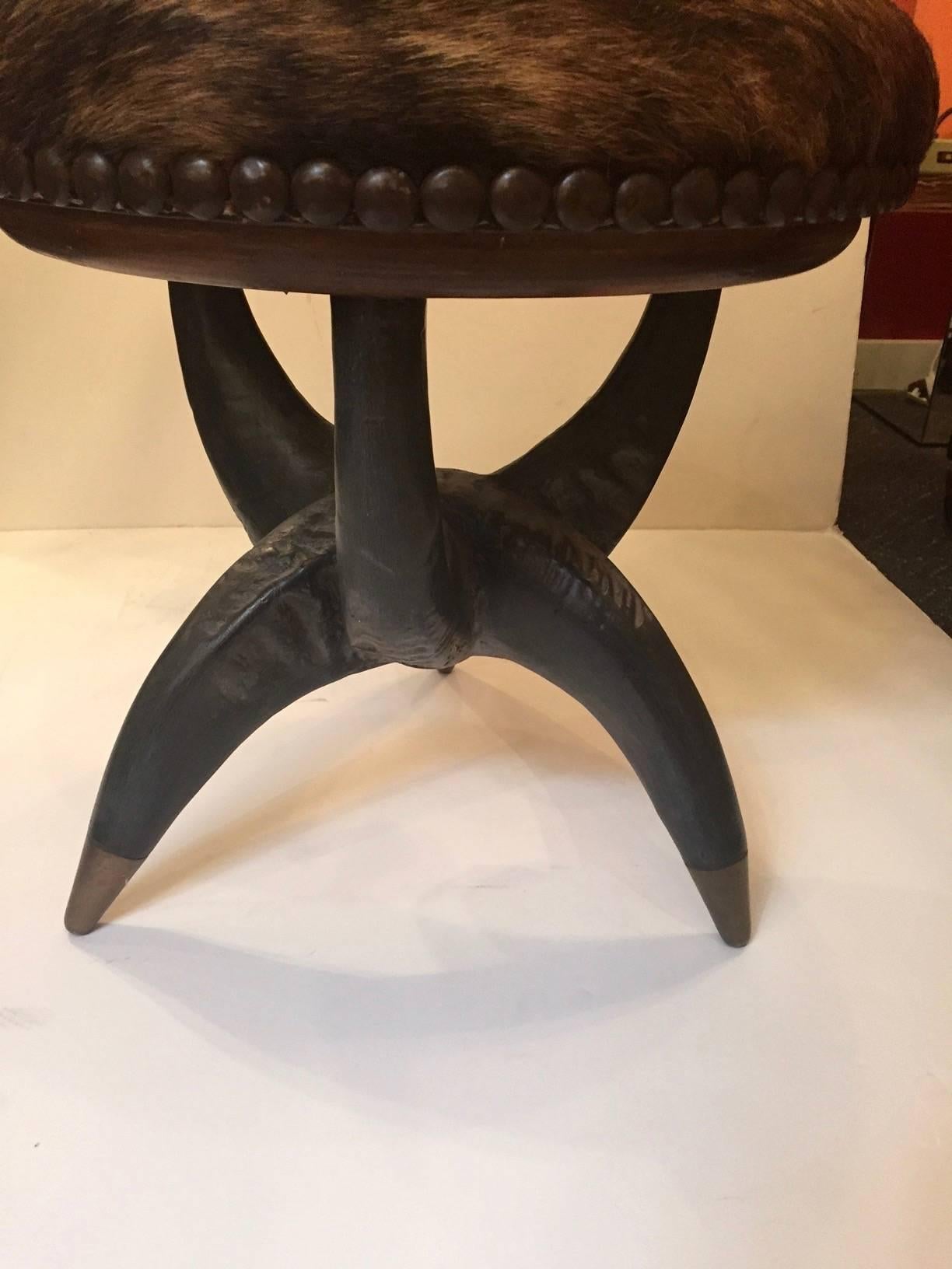 Great looking stool upholstered in light and dark brown cowhide with nailhead detailing and a cool grey black Horn base with brass caps.

RR